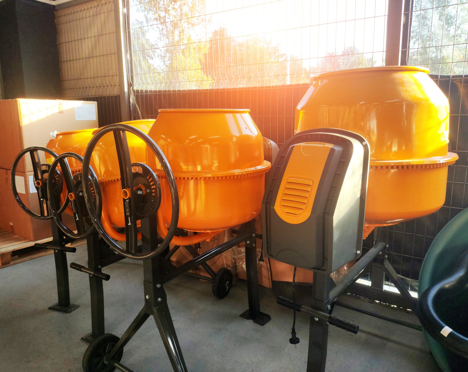 Sale of yellow concrete mixers in a store against the backdrop of a window with a sunset, indoors