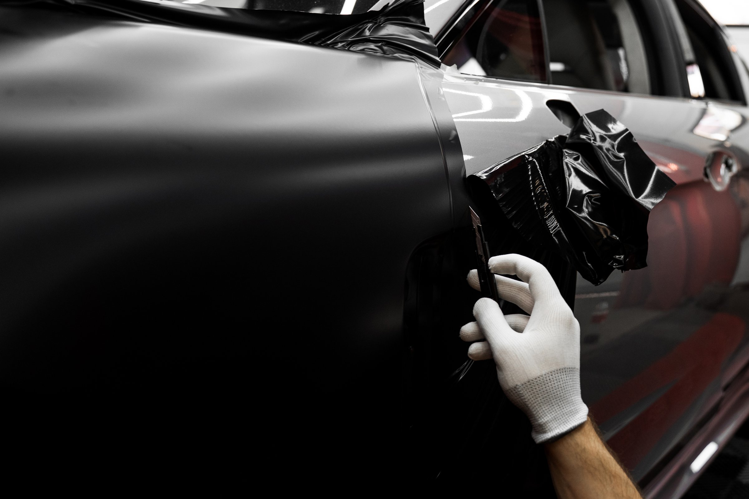Trimming edges helps maintain clean finish. Vinyl edge cutting in detailing center. Applying wrap with precision cutters shapes vinyl. Clean cuts enhance aesthetics and prevent peeling