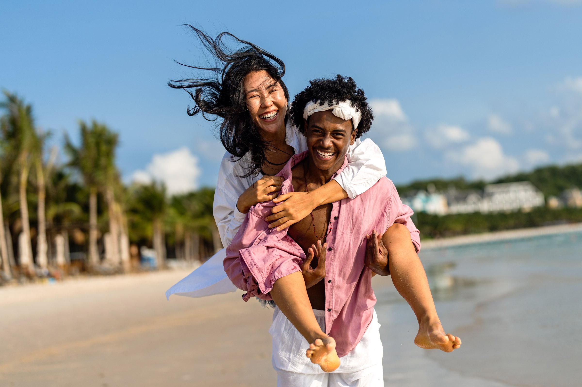Interracial couple enjoying a romantic beach getaway, embracing love, laughter, and togetherness in a tropical paradise