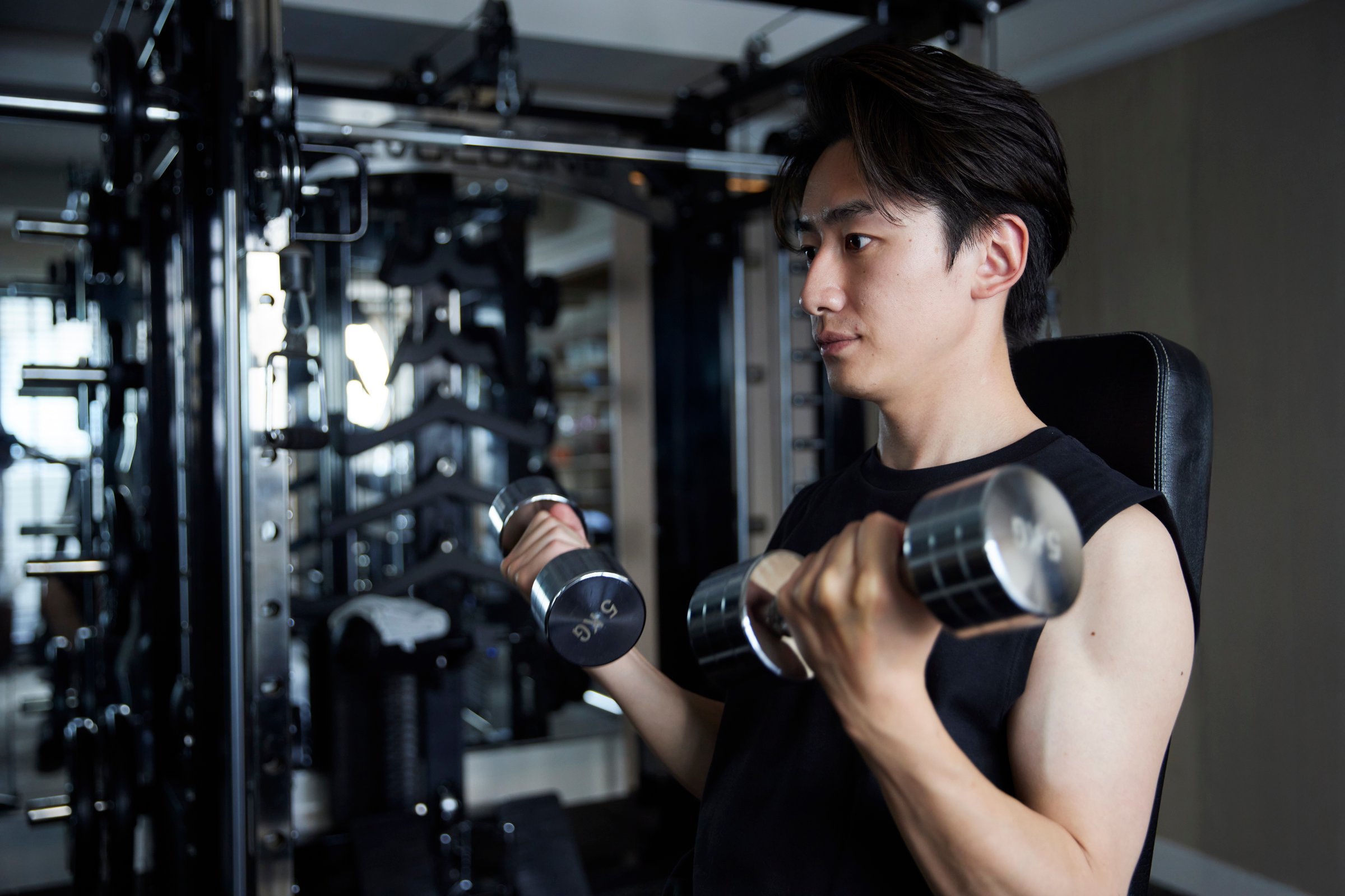 Young Japanese man in sportswear doing strength training at a fitness gym