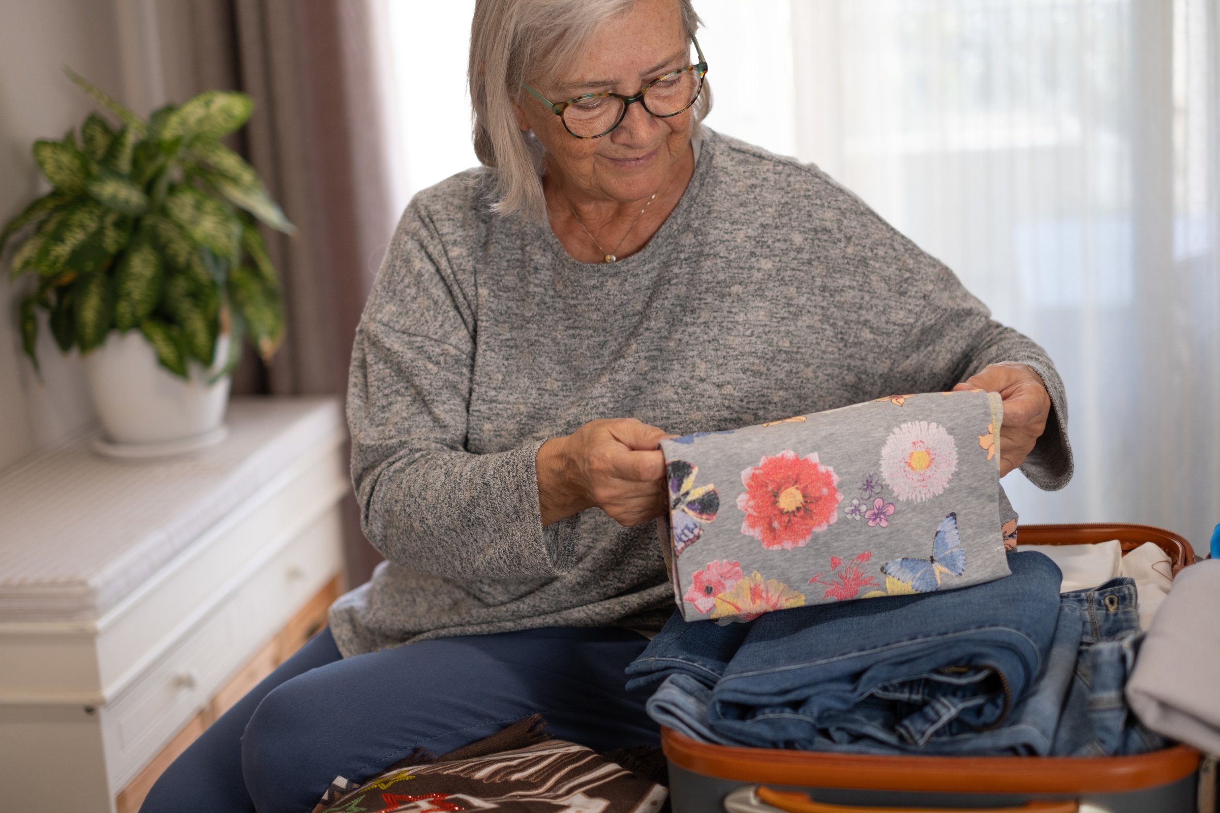 Full suitcase concept, elderly woman packing, preparing luggage case in bedroom for weekend or journey, luggage of clothes, travel trip