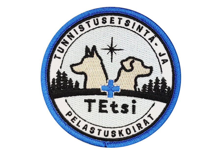 Circular patch with two dog silhouettes, a star, trees, and blue medical cross. Text reads Tunnistuset-sinta- ja Pelastuskoirat.