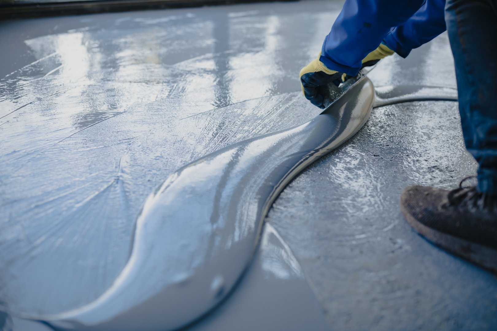 Worker expertly spreading resin on a smooth concrete surface
