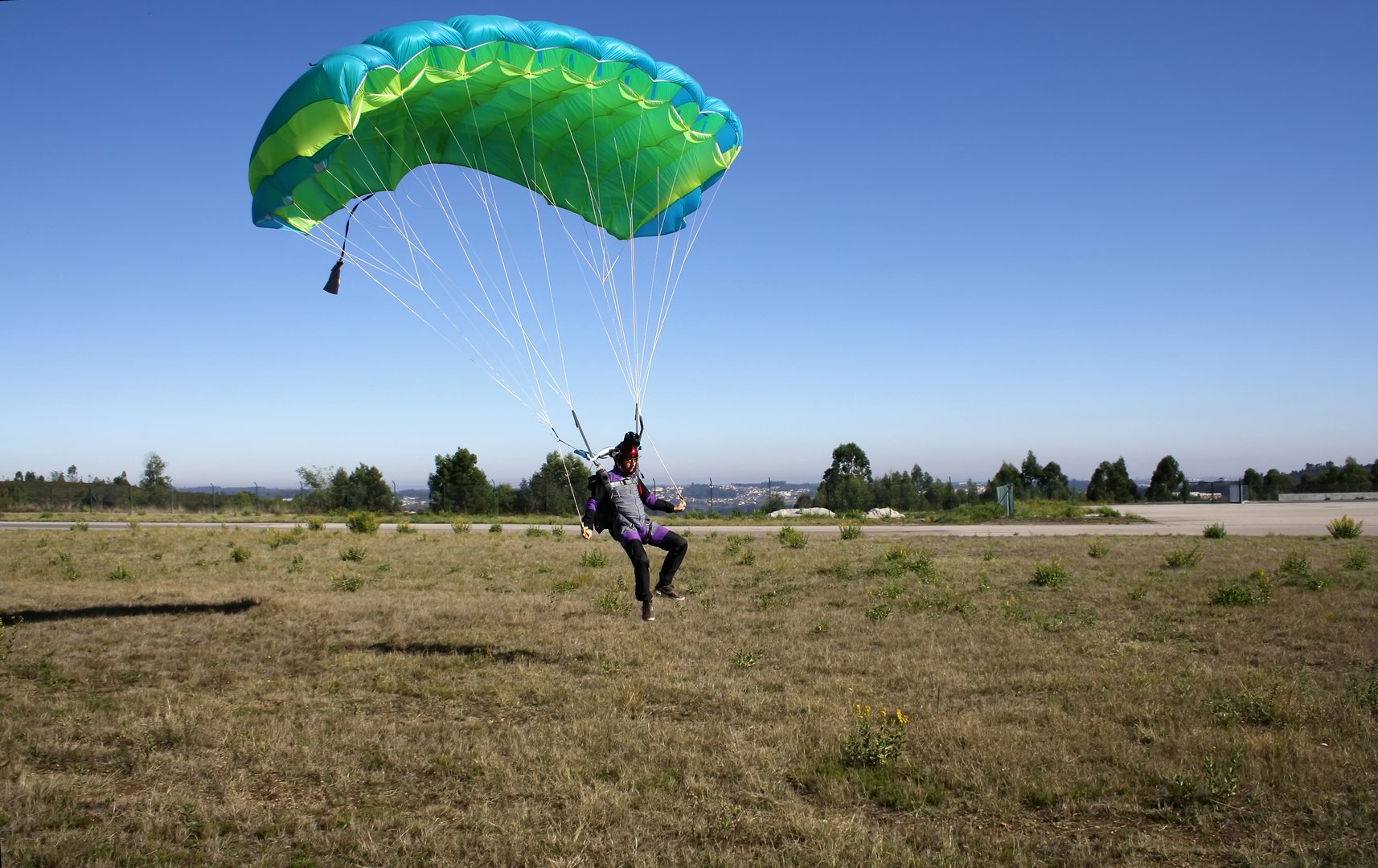 Paracaidista aterrizando su paracaídas en el suelo