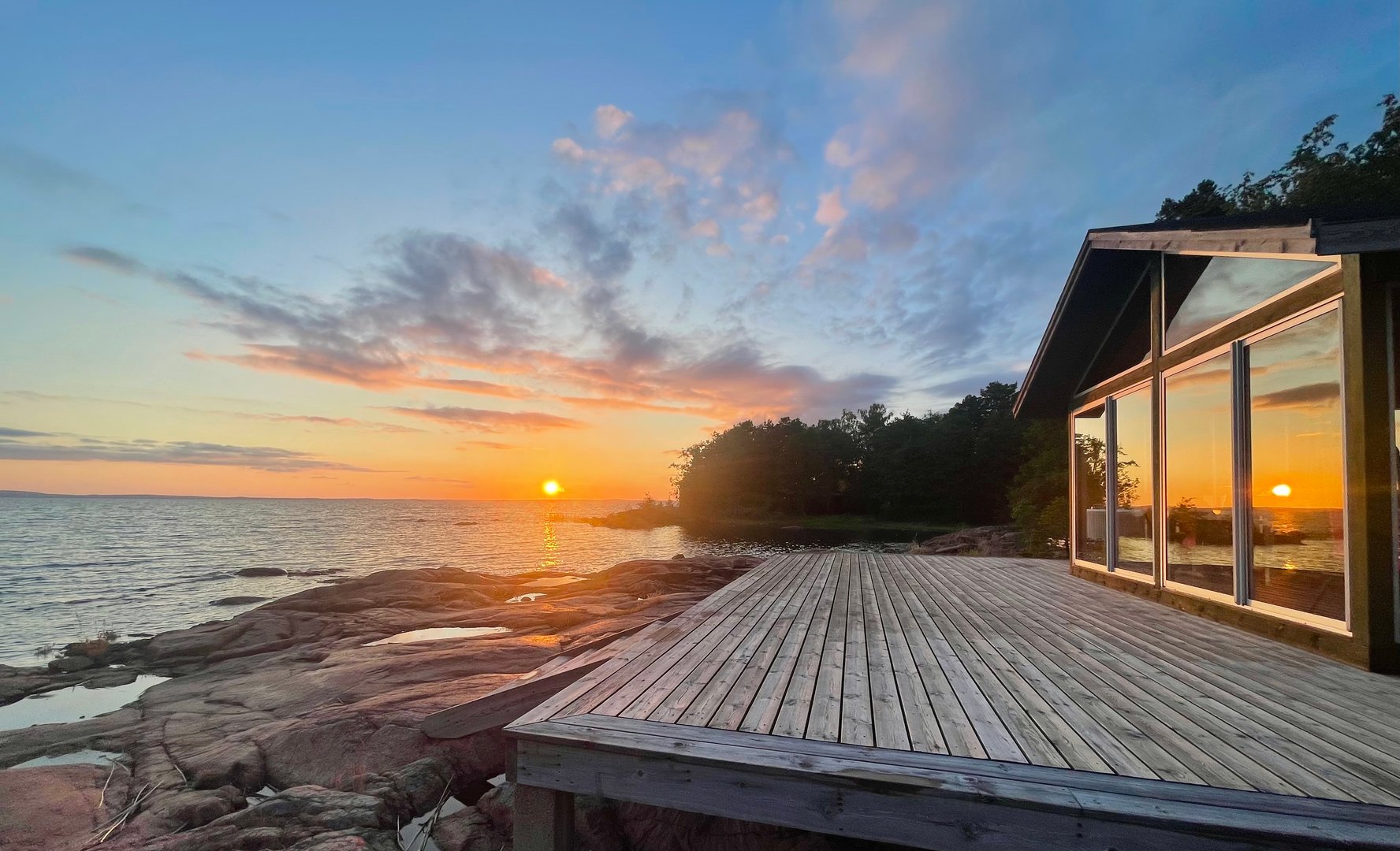 Cottage by the sea with sunset reflected in windows