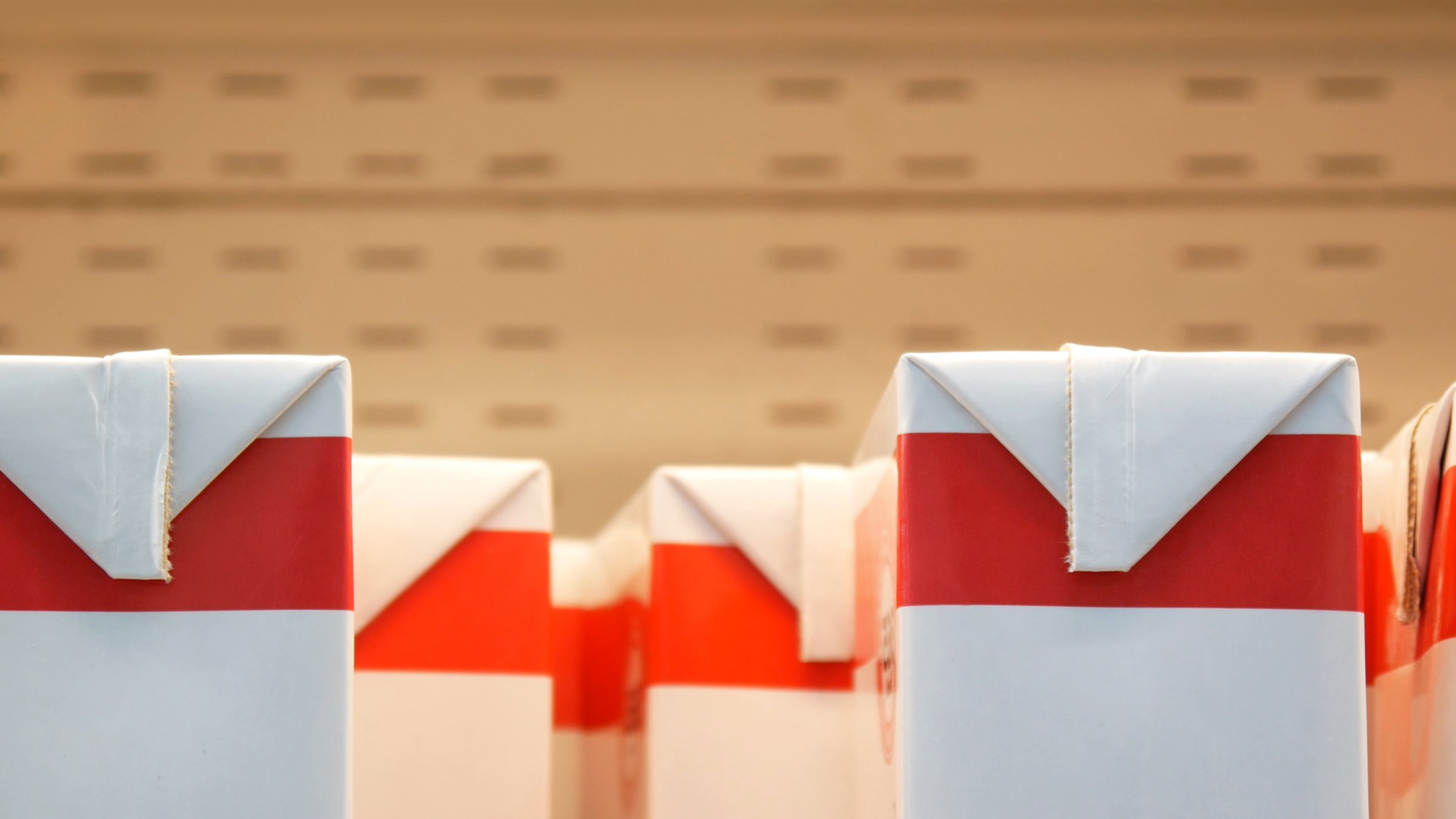 Many red white packages of milk on a grocery store shelf close-up