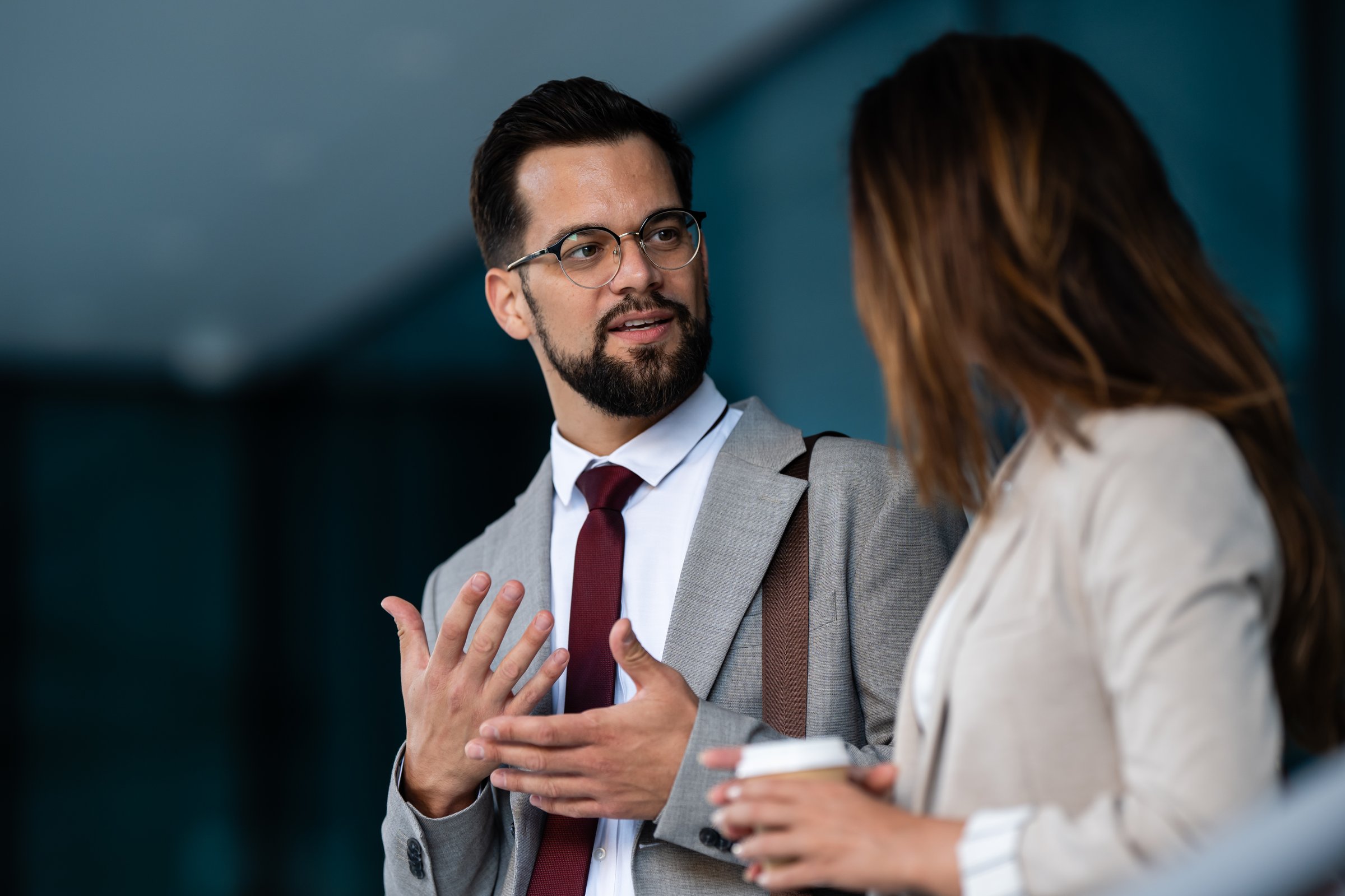 Businessman and businesswoman having informal conversation during coffee break outside office building