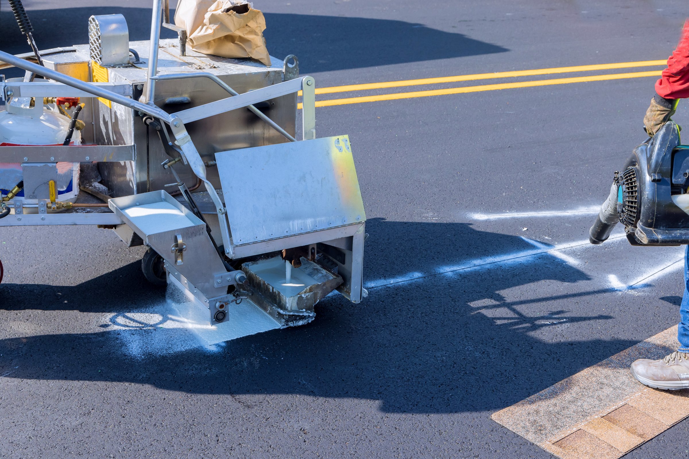 Road worker thermoplastic spray marking machine painting work on the street