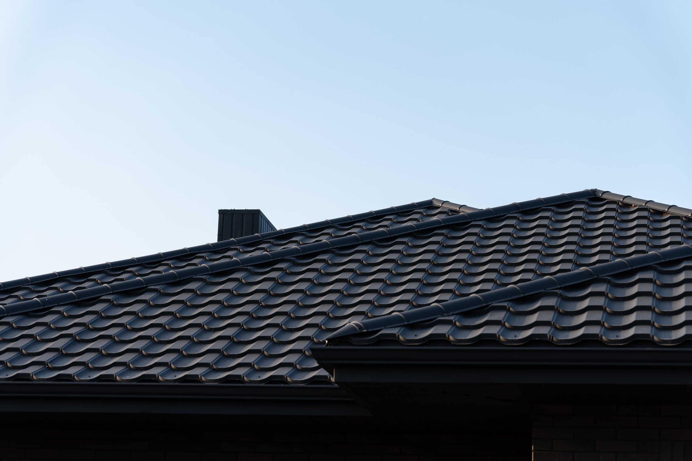 The image showcases a modern roof featuring sleek black metal tiles