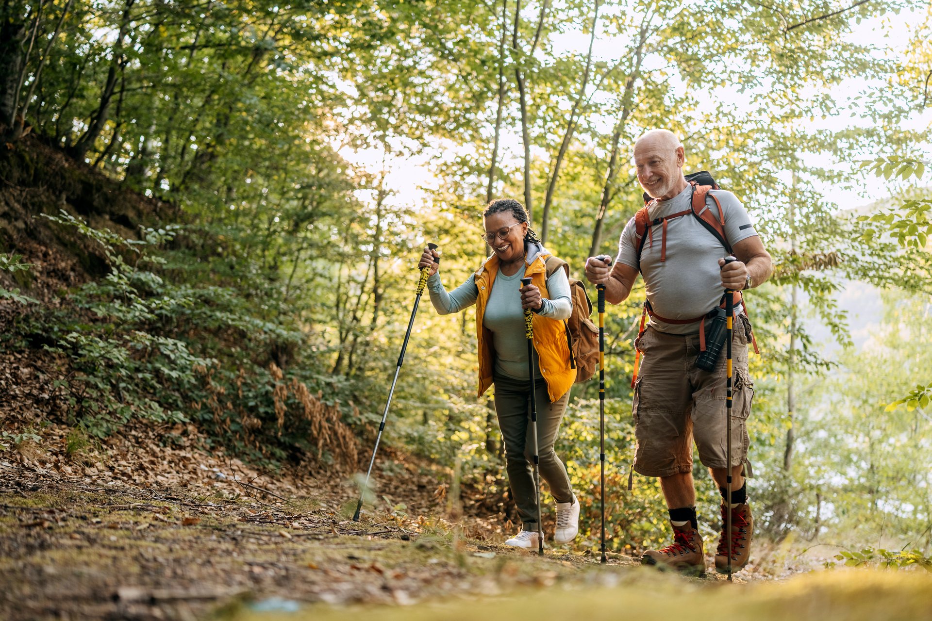 A smiling older couple hikes along a forest trail