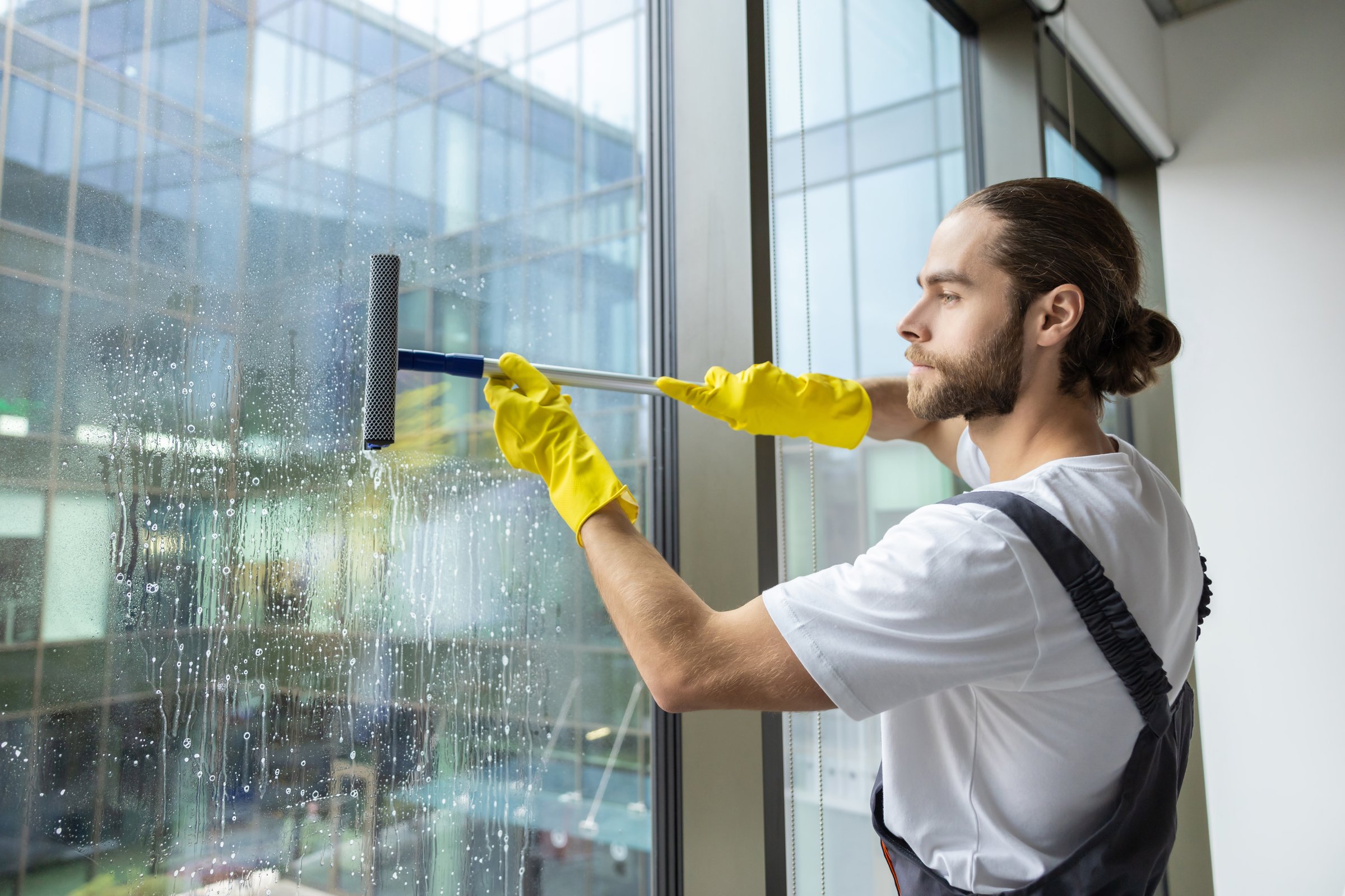 Windows cleaning. Cleaning person looking busy while cleaning the windows in the office