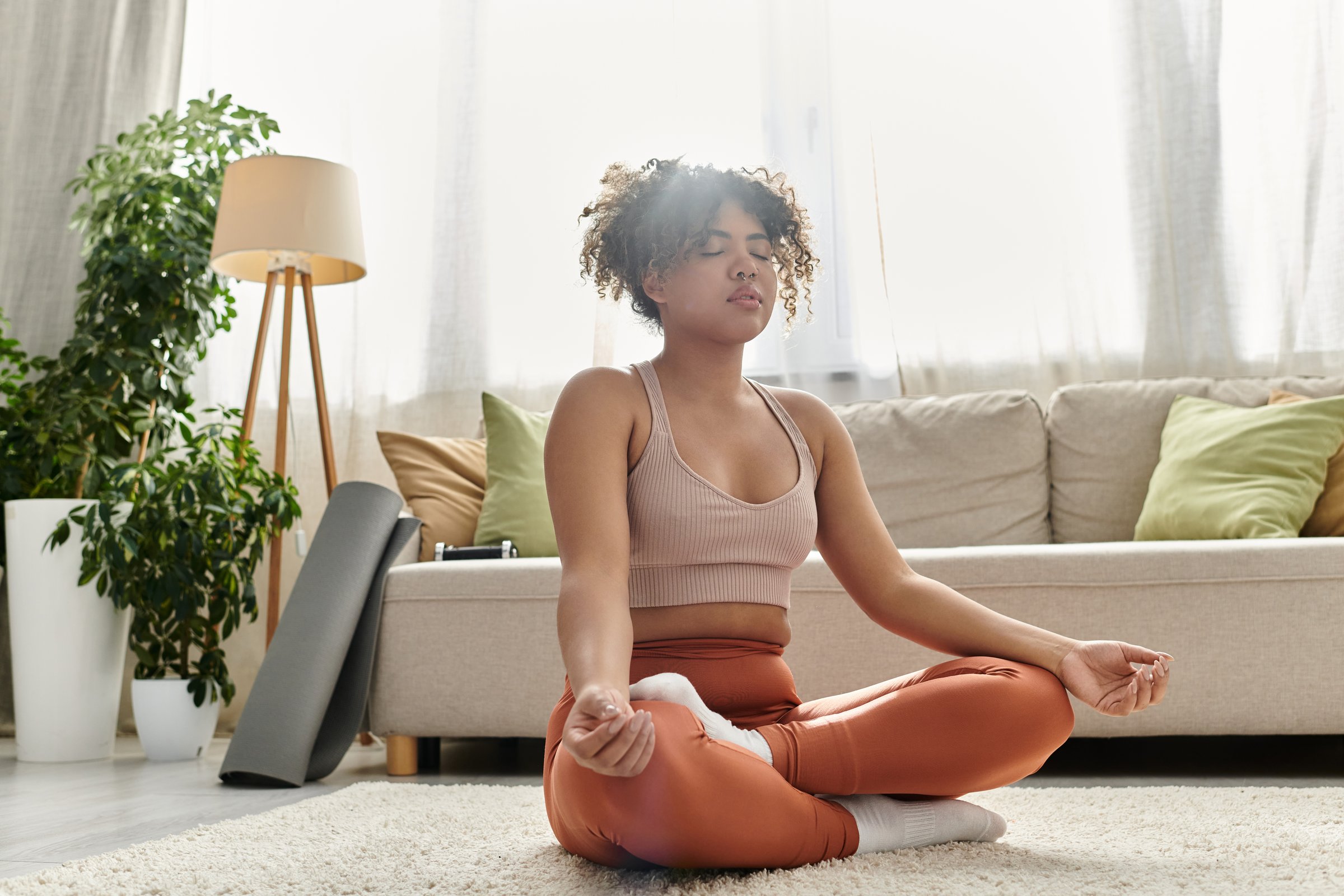 In a cozy living room, a young woman practices meditation, finding inner peace and relaxation.