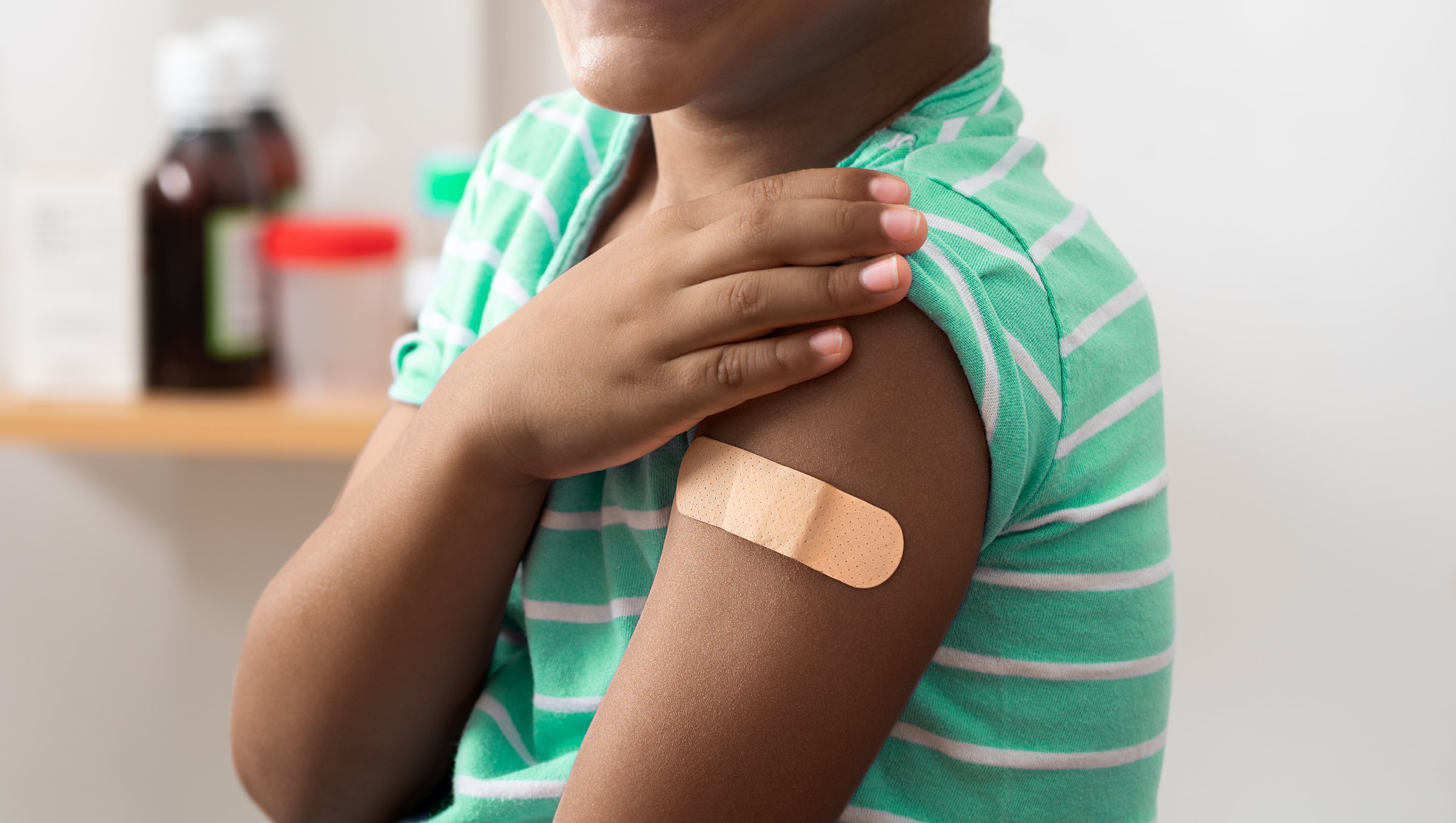 Vaccine and child with band aid on arm, medical shoulder injection dose and immunization bandage. Corona virus immunity, immune system cure or wellness and male patient healthcare vaccination.