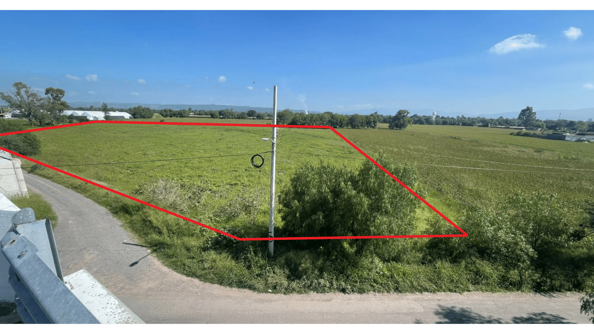 Open field with red outline highlighting a specific plot, seen from a higher vantage point on a sunny day.