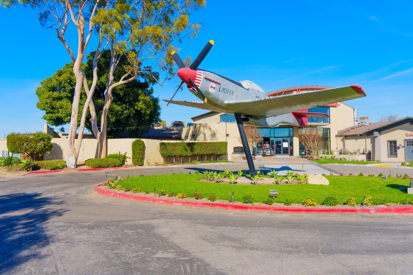 Los Angeles, California - January 6, 2025: Replica of a WWII P-51 Mustang plane prominently displayed outside a building in Los Angeles, California, surrounded by lush greenery.