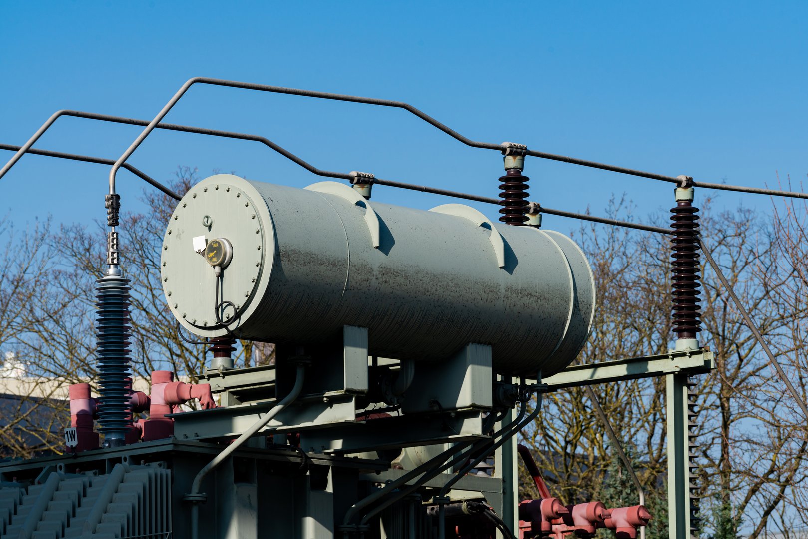 A large power transformer is positioned against a backdrop of a bright blue sky.