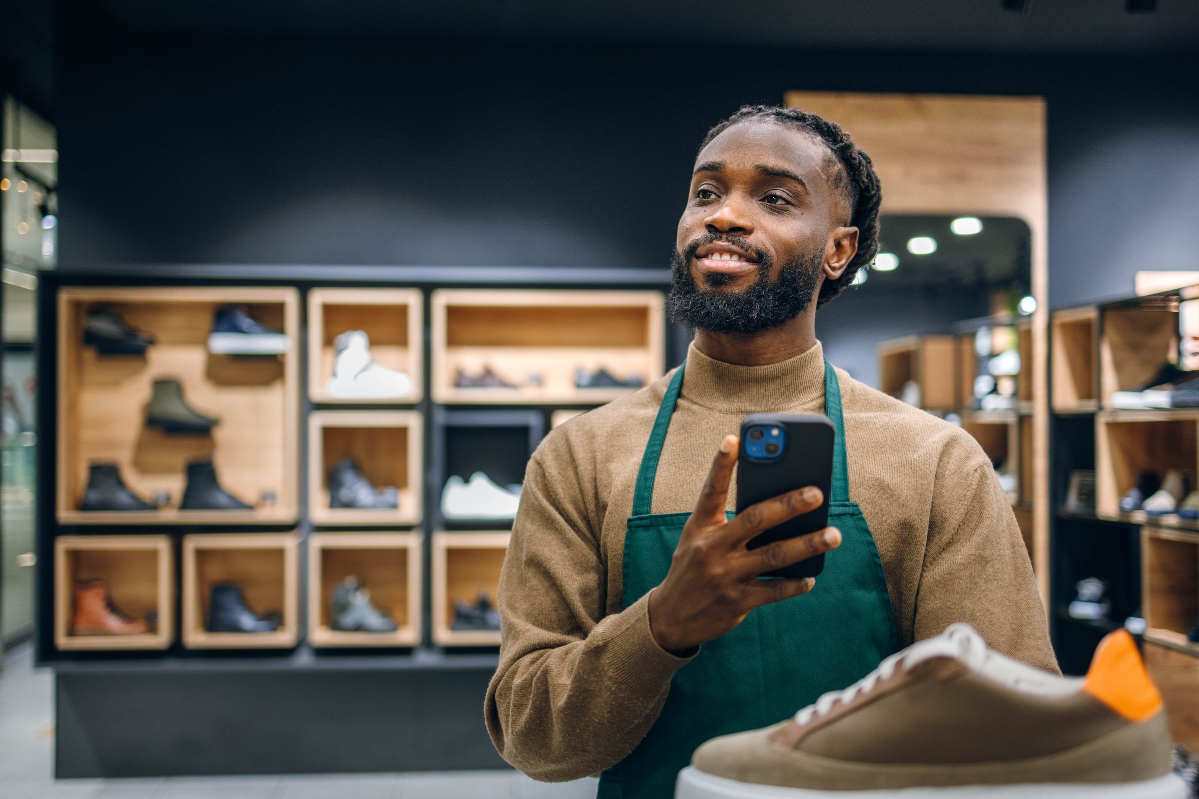 Sneaker salesman using phone and looking at sneakers