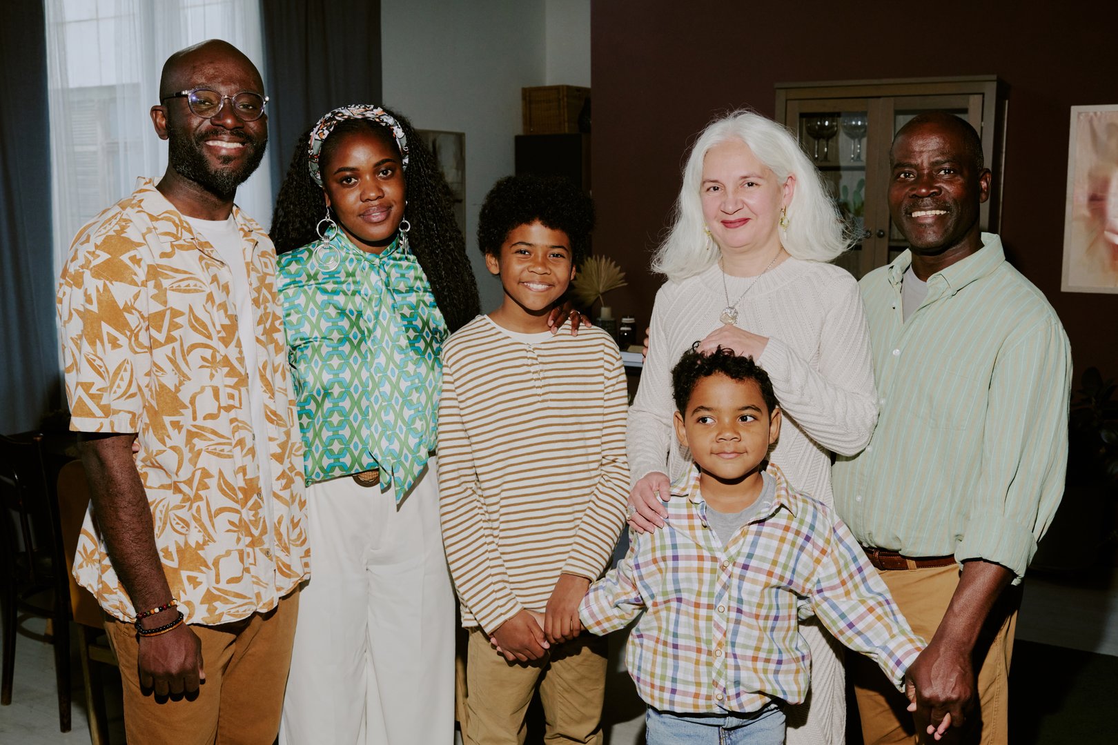 Portrait of beaming biracial family standing in living room of huge cottage and posing together