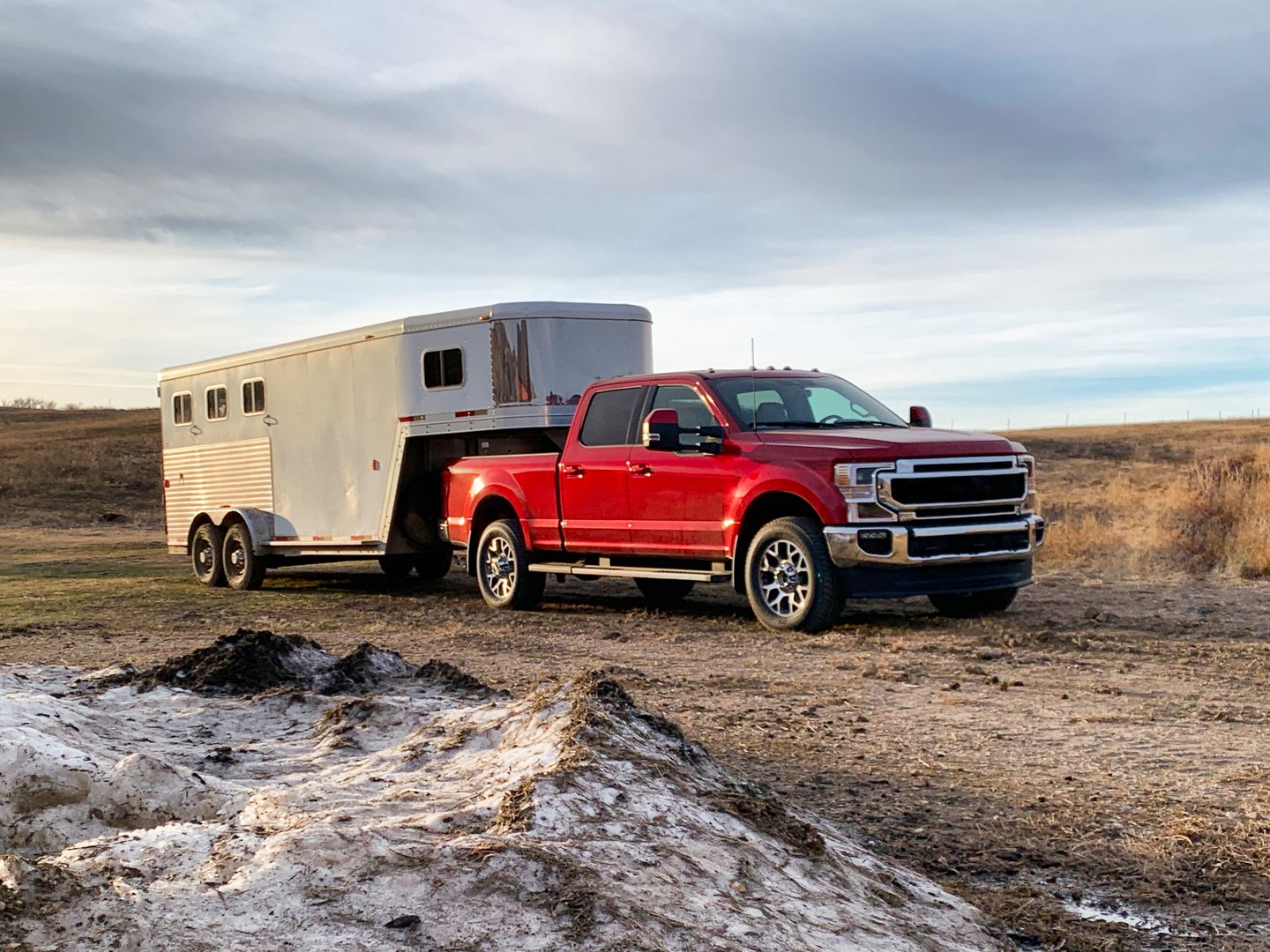 Red maroon one ton pickup truck hooked up to gooseneck slant load horse trailer.