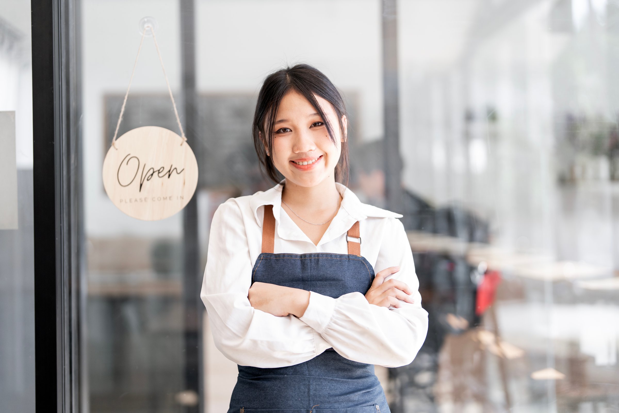Portrait of smiling waitress standing with arms crossed