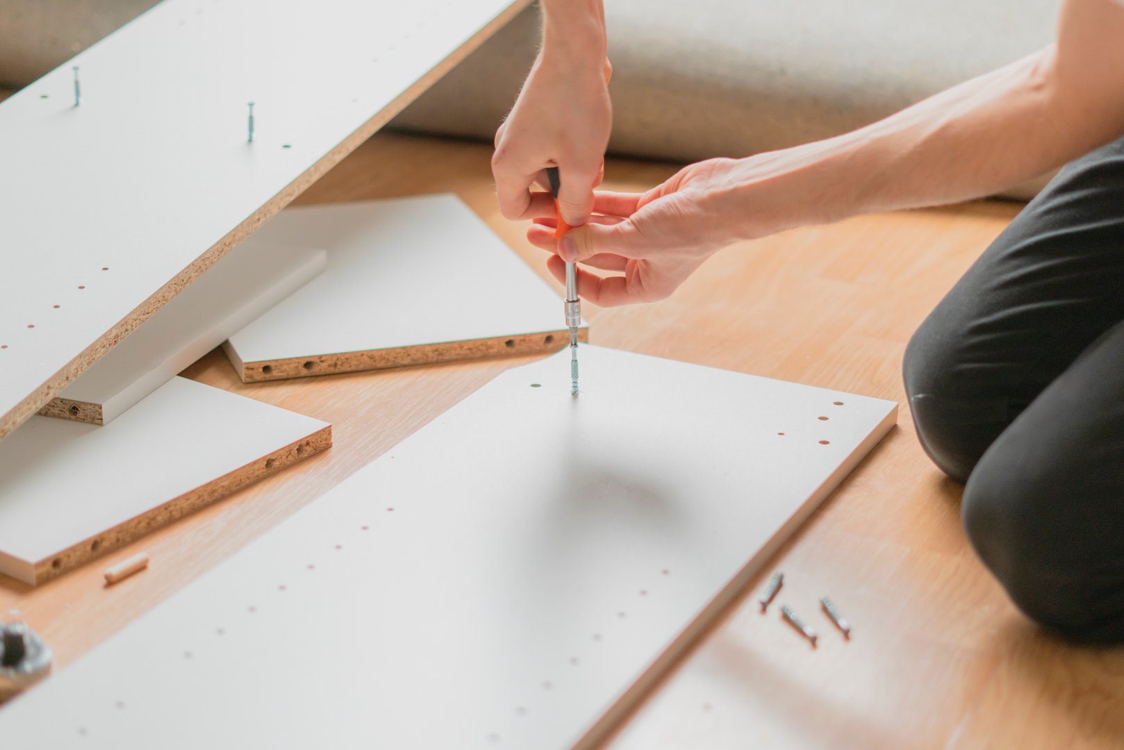 close up man assembling new furniture with a screwdriver