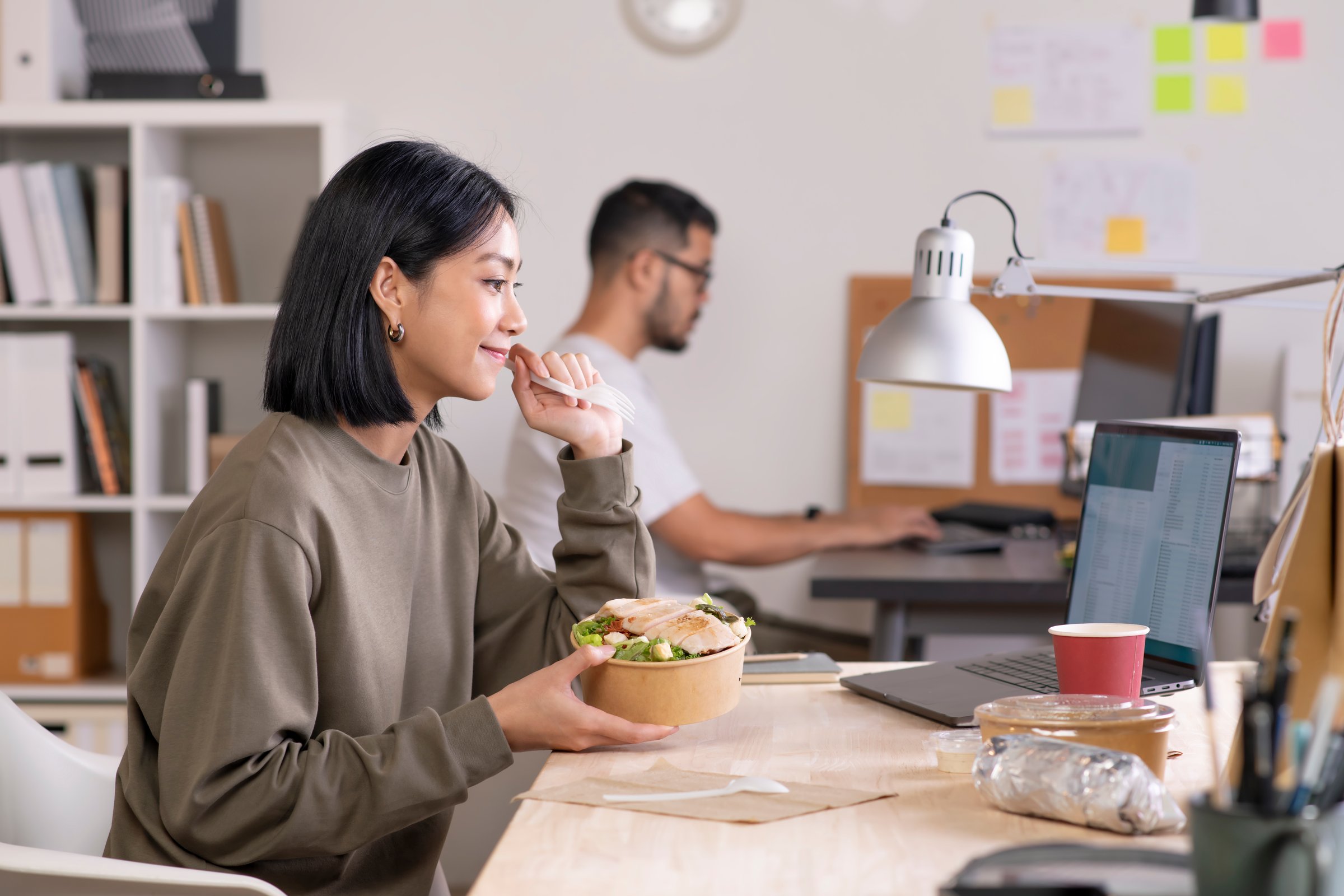 Asian woman eating healthy meal while working, Businesswoman having a lunch break at the office - sugarfree.space executive nutrition corporate stress resilience