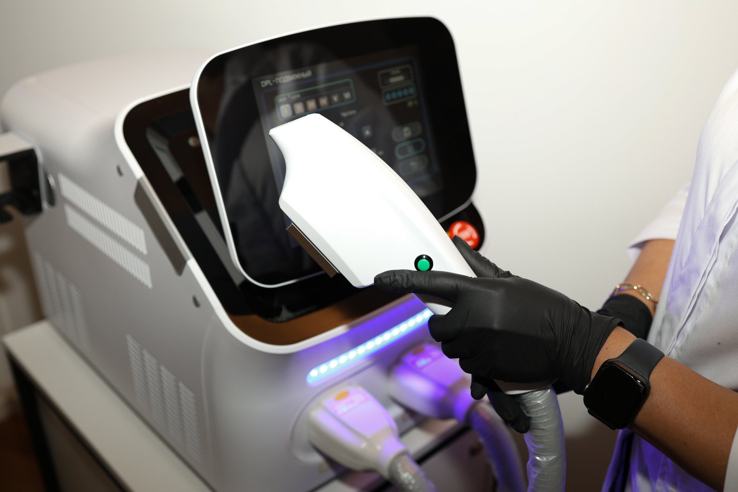 Close up of beautician hand in black glove holding ultrasound device for face lifting and skin tightening procedure. Young woman cosmetologist using modern cosmetology equipment in clinic.