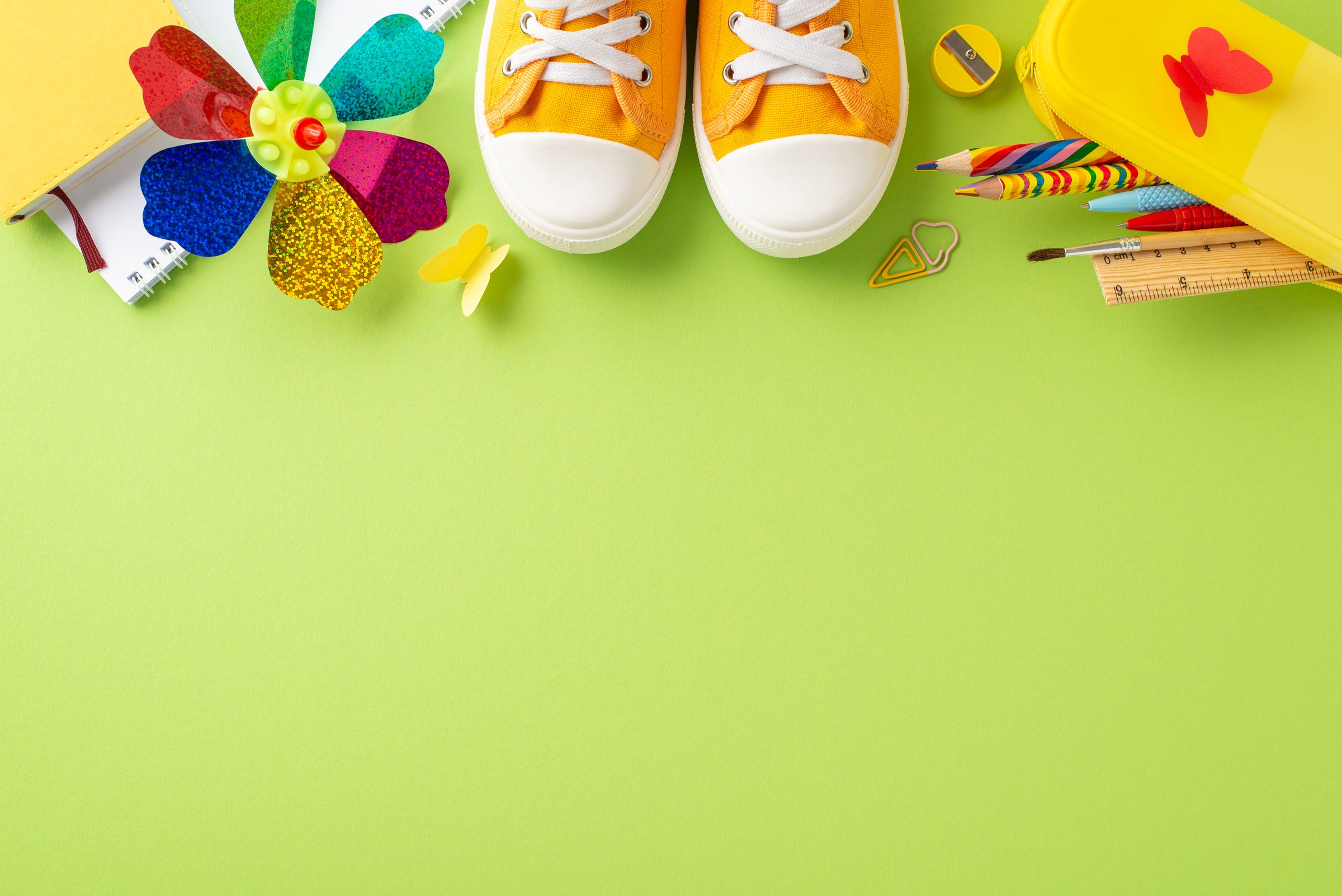 Vibrant display featuring school supplies and orange sneakers laid out against a striking green backdrop, symbolizing creativity and fun in learning