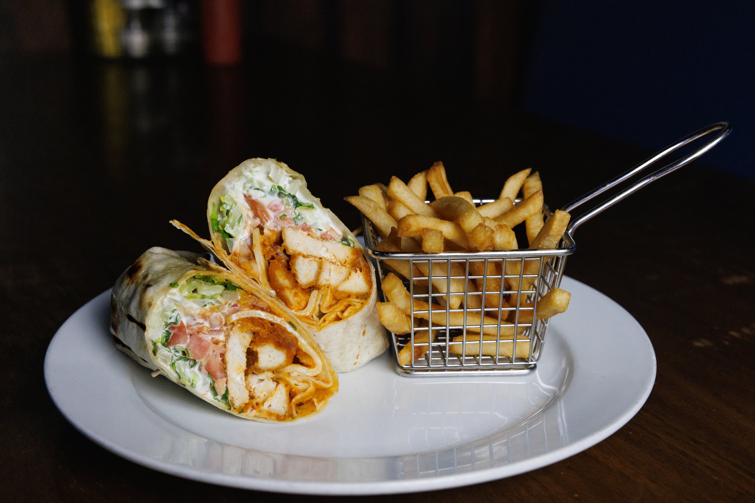 Fish salad wrap with fries on a white plate in a bar / pub