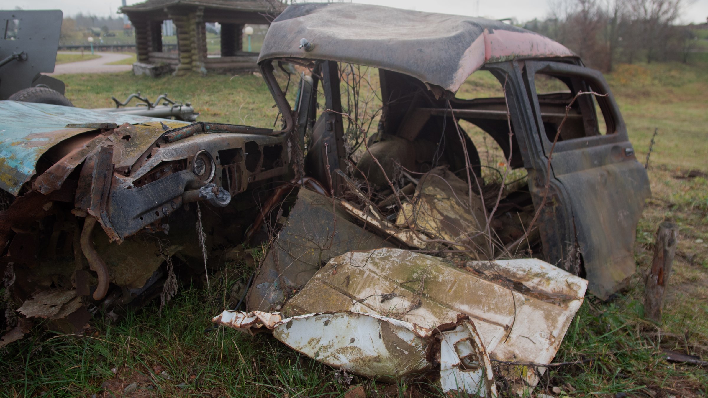 rusty vintage car wreck in field, collapsed roof and crushed fenders, shattered glass and peeling paint,