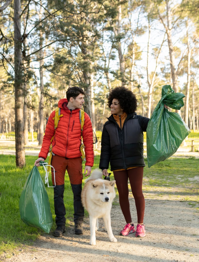 young multiracial activist couple with their dog in the forest celebrate collecting waste and garbage - Couple recycling environmental cleanup