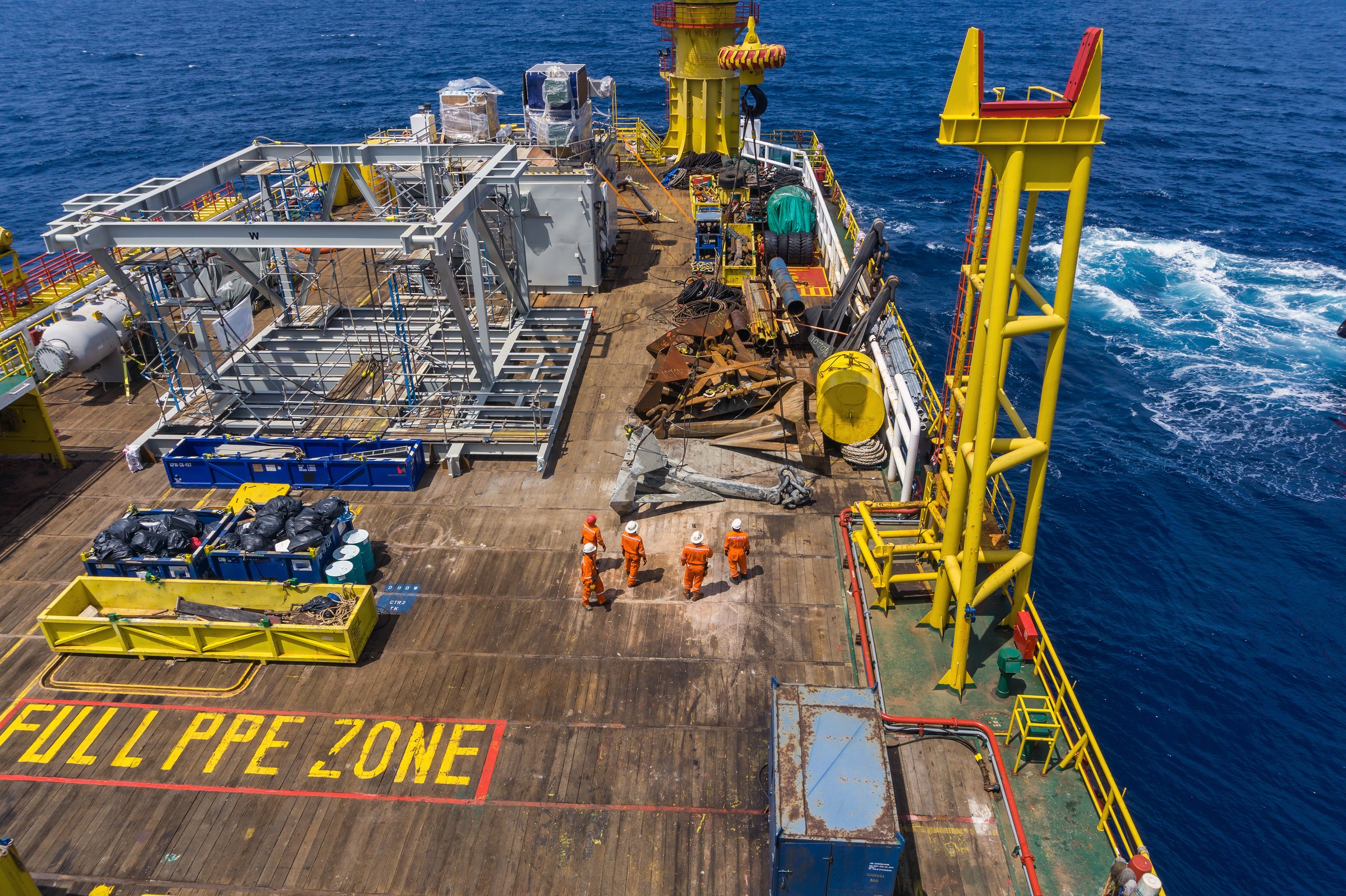 Offshore crews handling and lifting anchor for deployment on construction barge at oilfield Terengganu, Malaysia