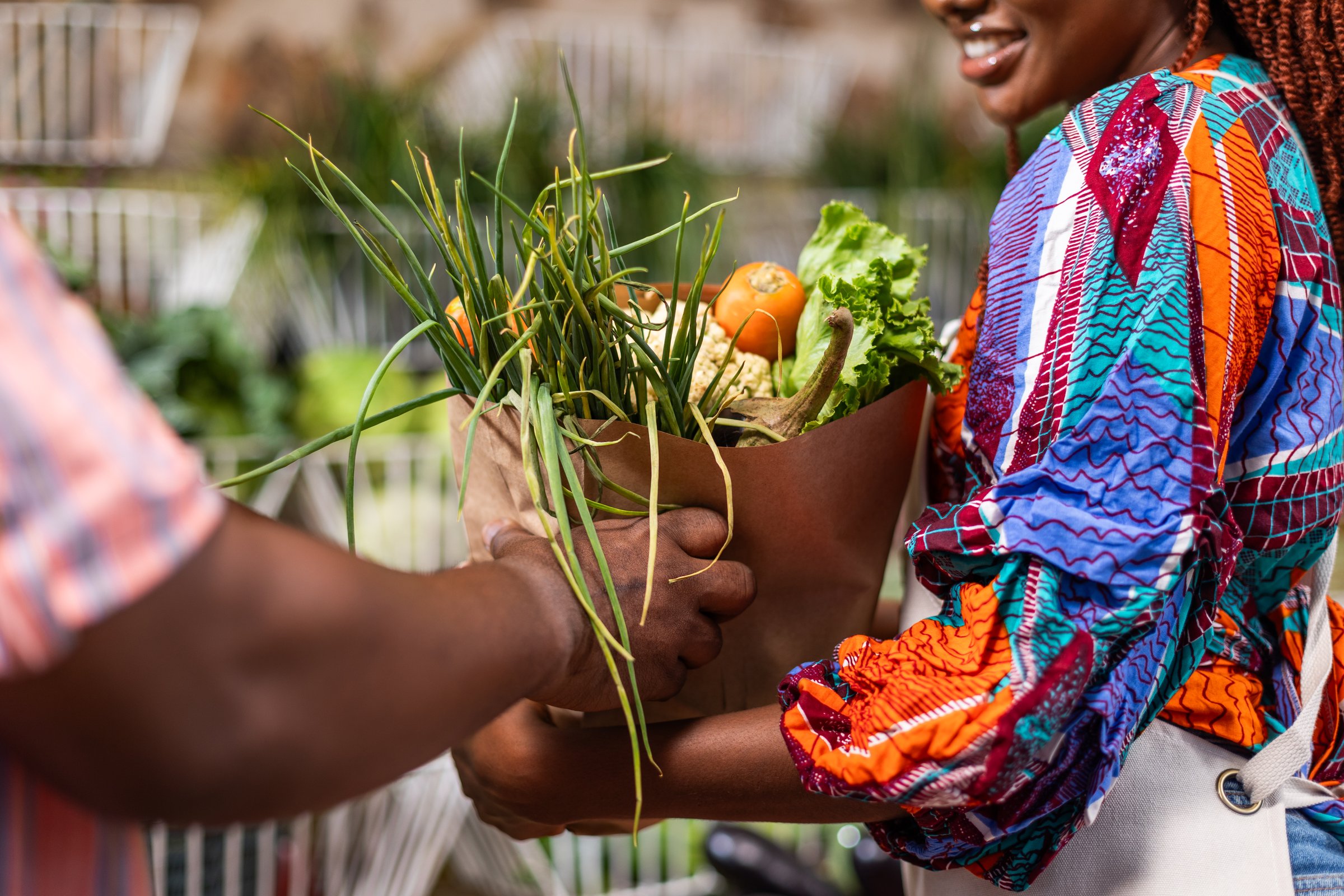 Eco-Friendly Market, Sustainable Shopping, Customer receives a bag of fresh produce from African female vendor at local fruits and vegetable market.