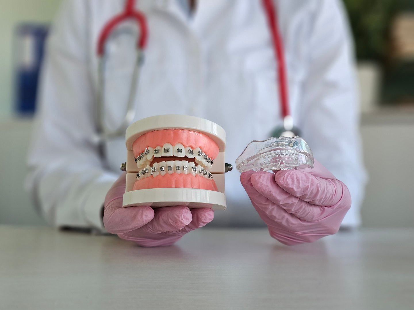 Orthodontist demonstrating dental braces with a model and clear aligner during a consultation in a modern clinic