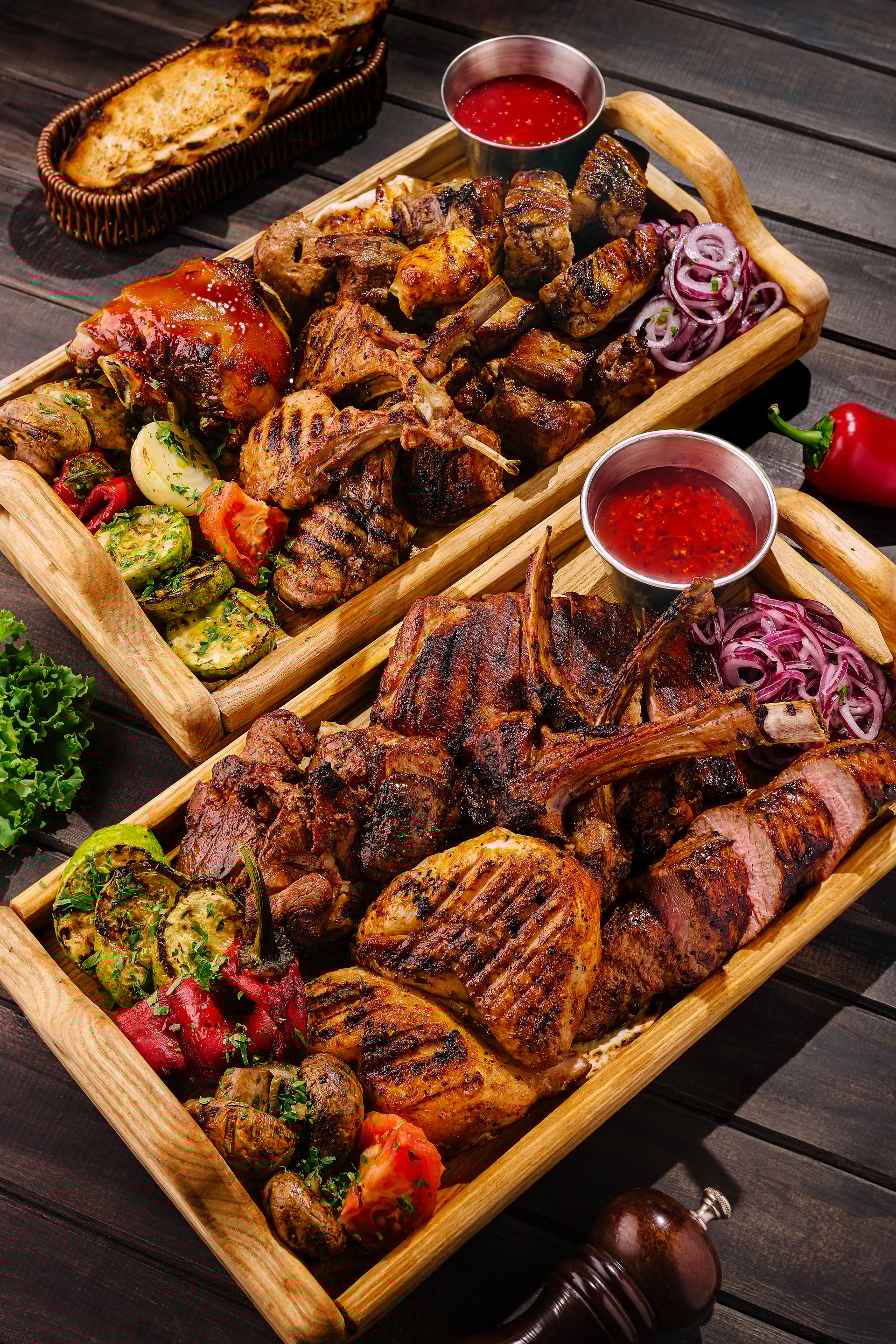 Succulent cuts of grilled meats, including ribs, chicken, and steak, presented on a wooden platter alongside colorful vegetables and dipping sauces, perfect for sharing at a gathering.