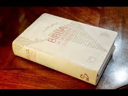 A Spanish Bible resting on a wooden table with a light-colored cover featuring embossed text.