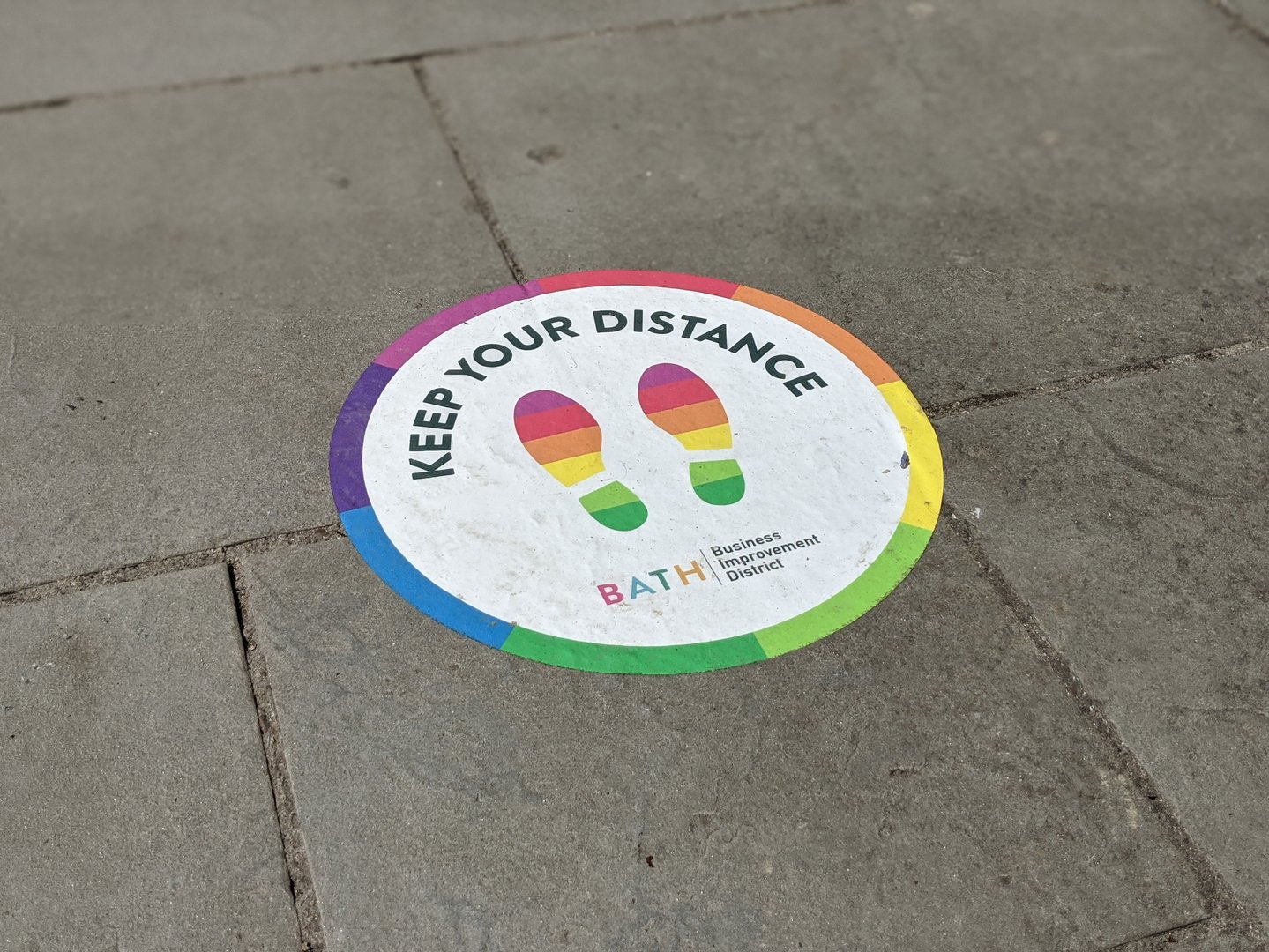 Bath Spa, England, UK - June 17, 2020: Signage and stickers have been introduced around the city as a new social distancing measure. Markers have been utilised outside building entrances to help customers and the public queue safely as shops and restaurants begin to re-open following the COVID-19 (Coronavirus) lockdown.
