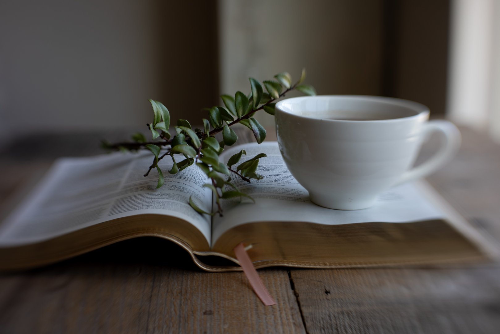 Bible on wooden table with tea