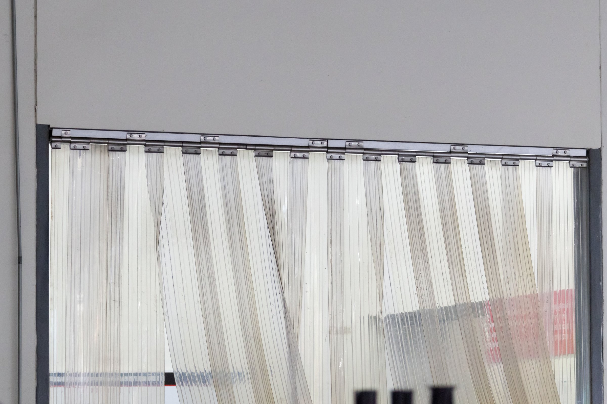 A window with a plastic curtain hanging in front of food cargo.