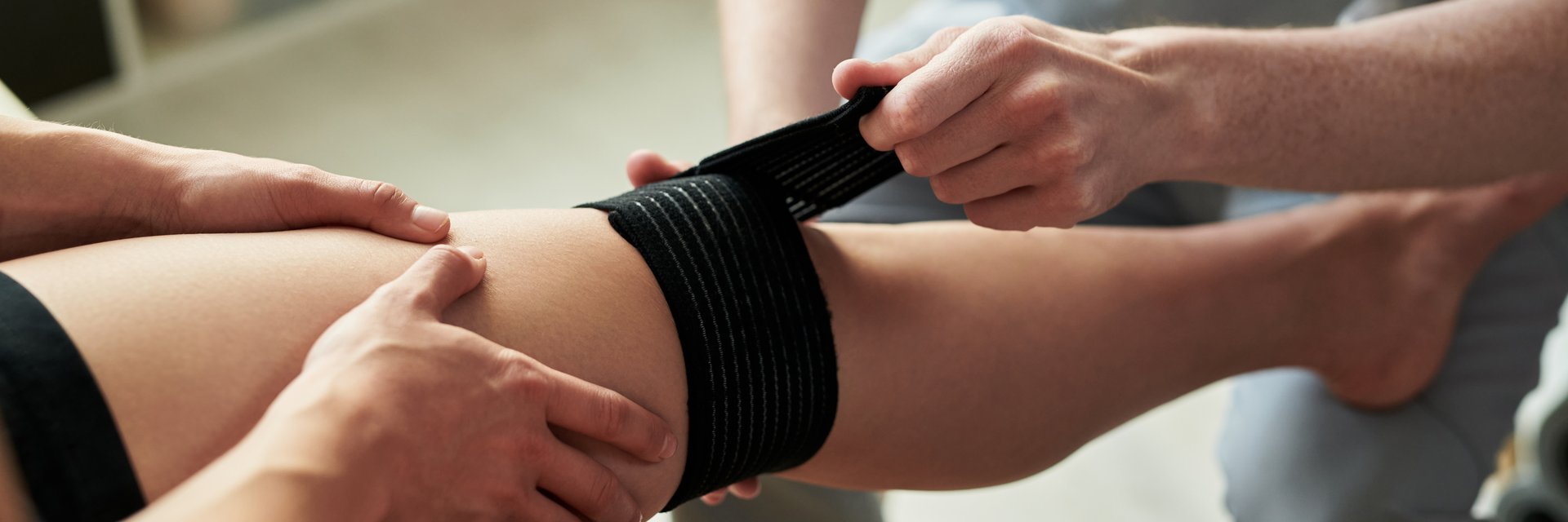 Close-up of hands wrapping elastic bandage around injured leg during rehabilitation process with careful attention to detail aiding recovery