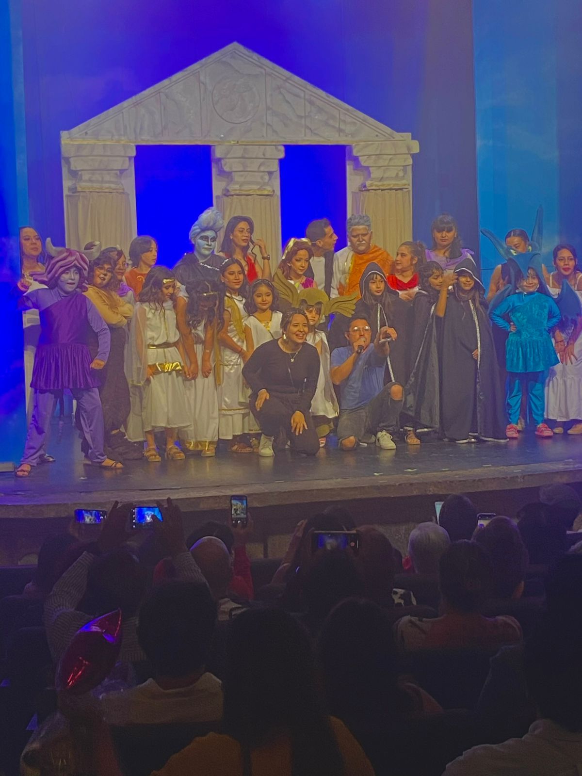 Full length portrait of group of children taking final bow on stage in school play production