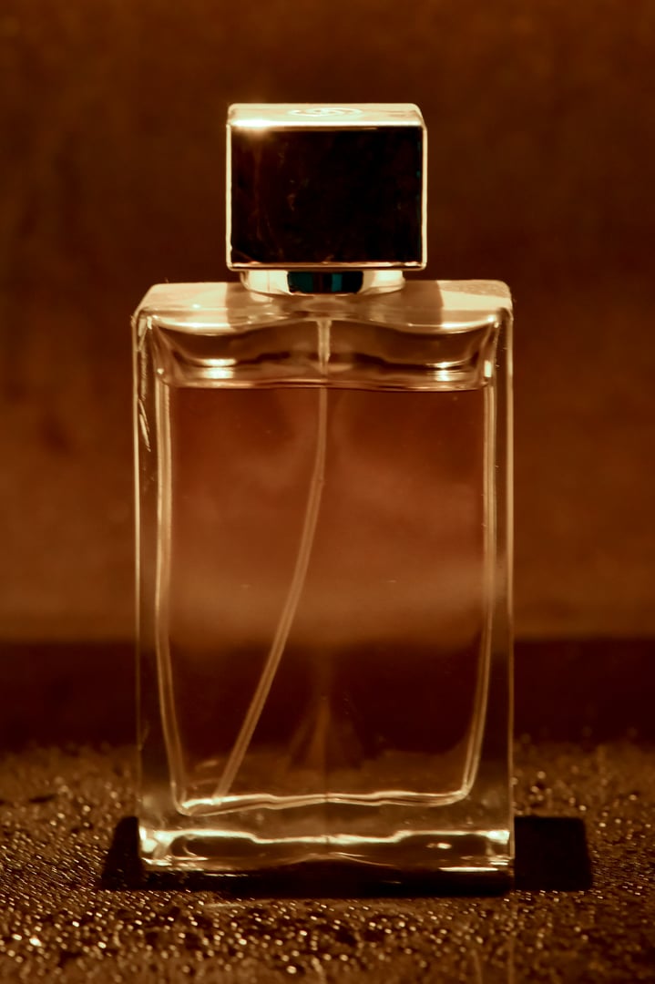 a clear glass perfume bottle with a silver-colored cap.