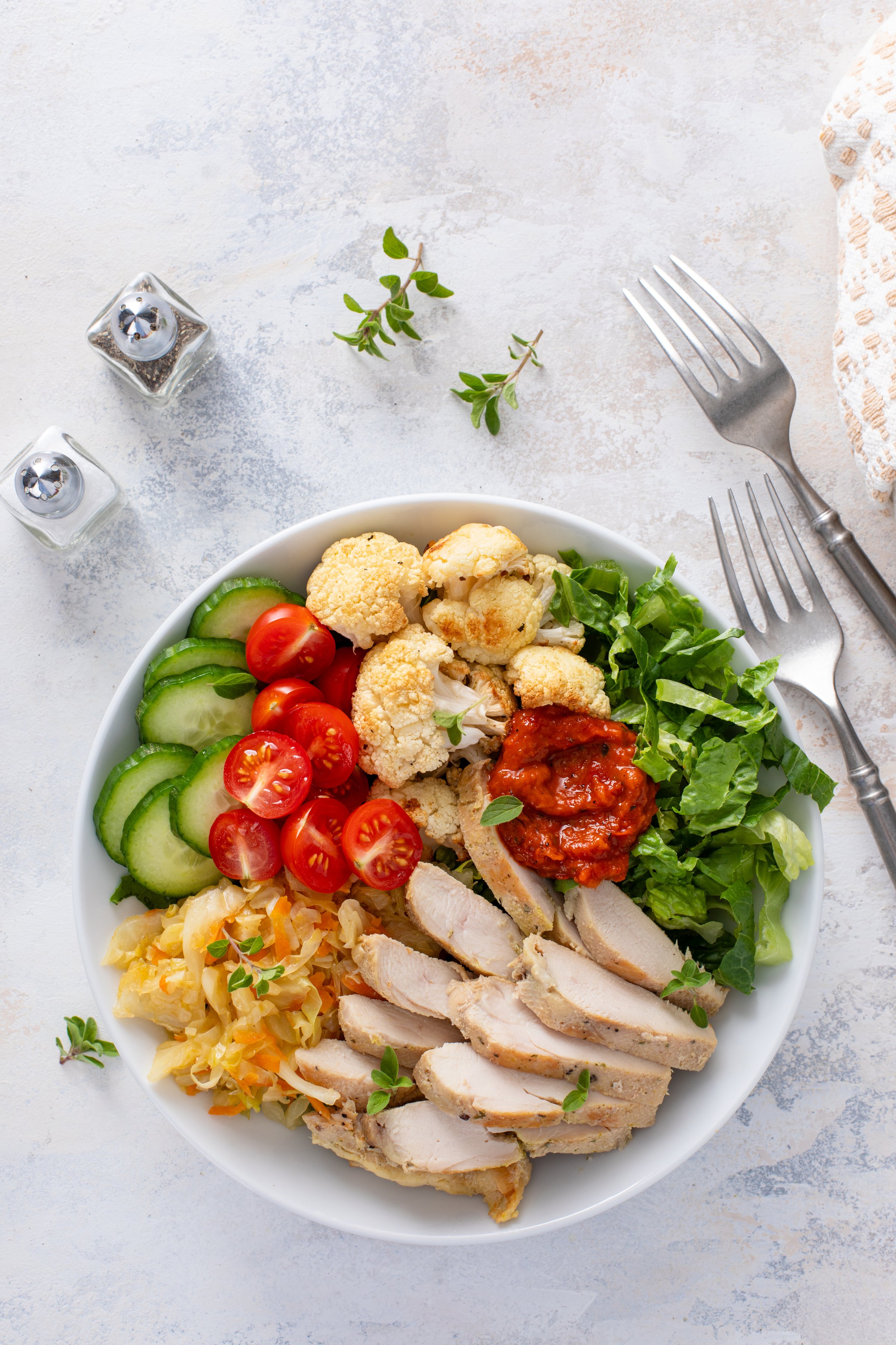 Healthy lunch bowl with grilled chicken, roasted cauliflower, lettuce and fresh vegetables