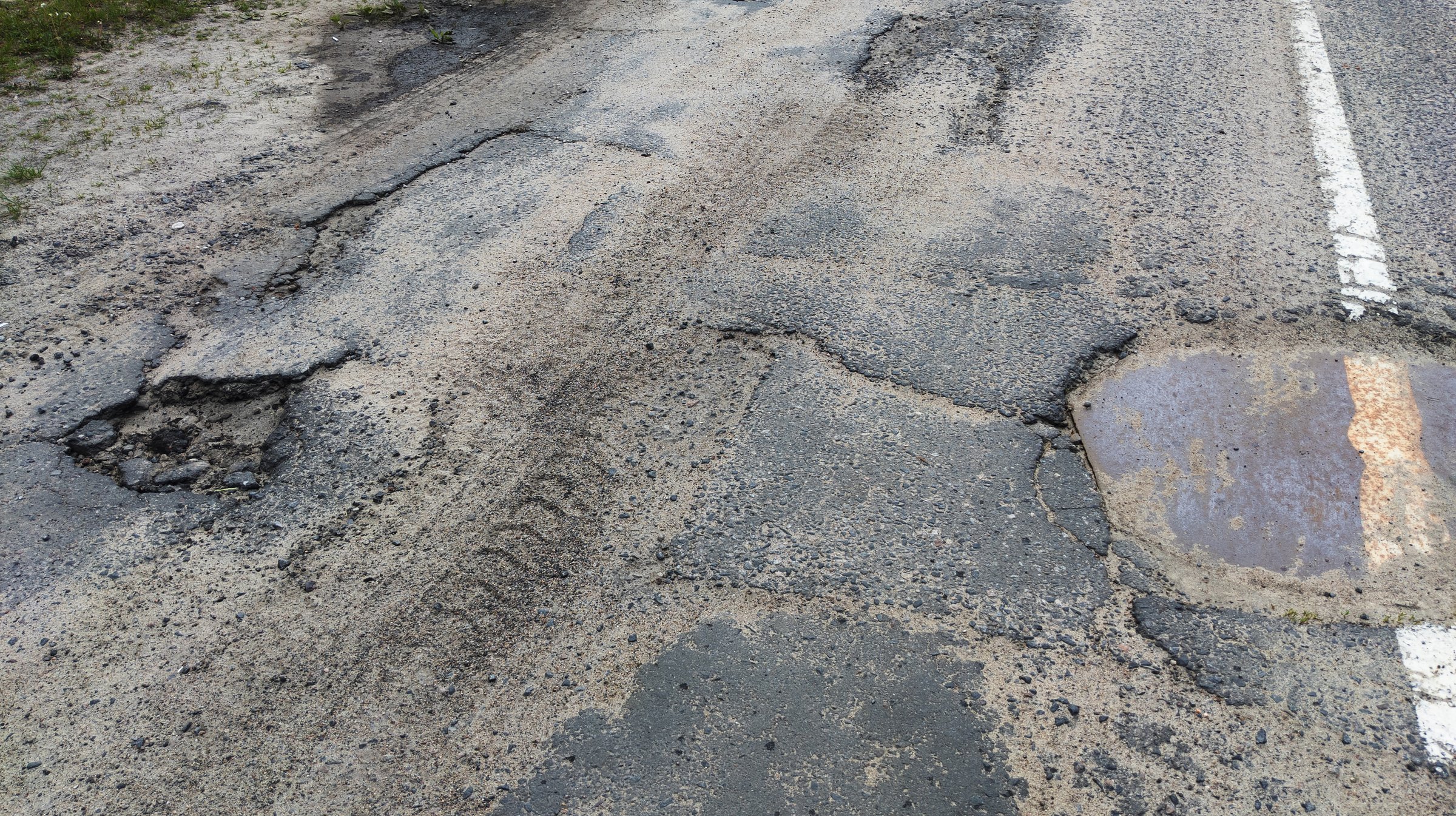 Dangerous potholes in the asphalt town road. Road damage, broken