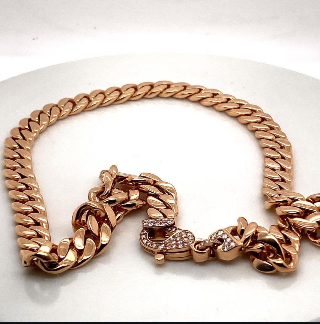 Gold chain necklace with a textured link design and a rhinestone-encrusted clasp on a white surface.