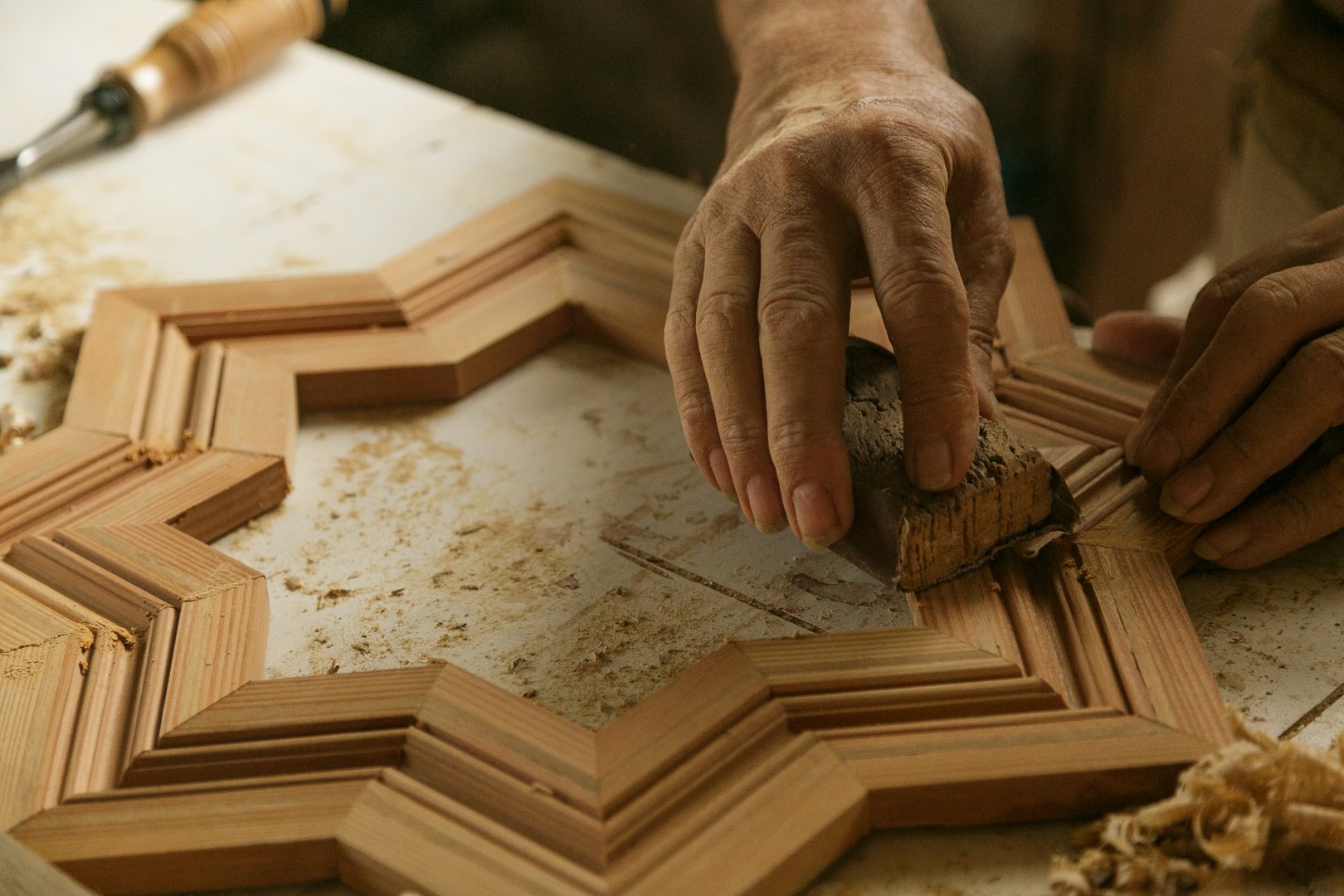 A Skilled Craftsman Is Expertly Shaping A Beautiful Wooden Frame In His Workshop Environment