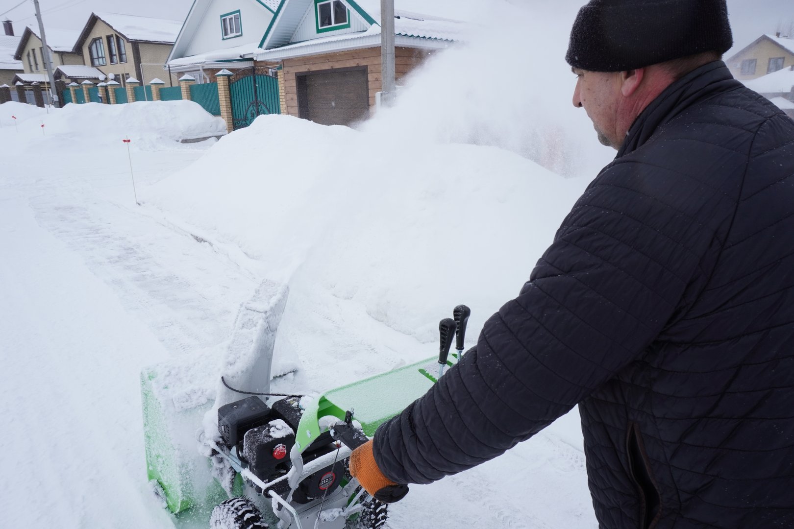 A man cleans snow in the winter in the courtyard of the house, man cleaning snow with a snow blower