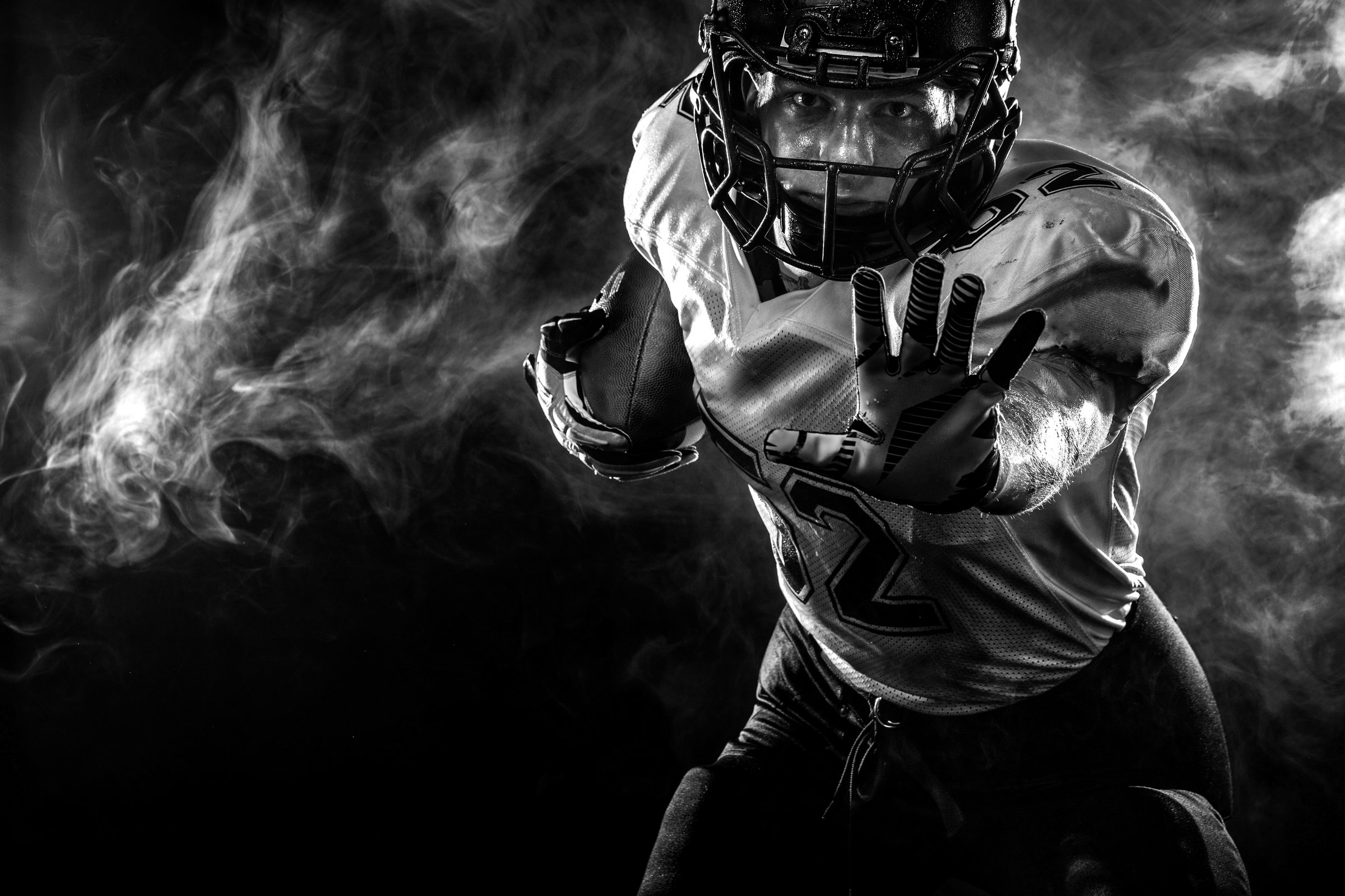 American Football player on stadium with smoke and lights.