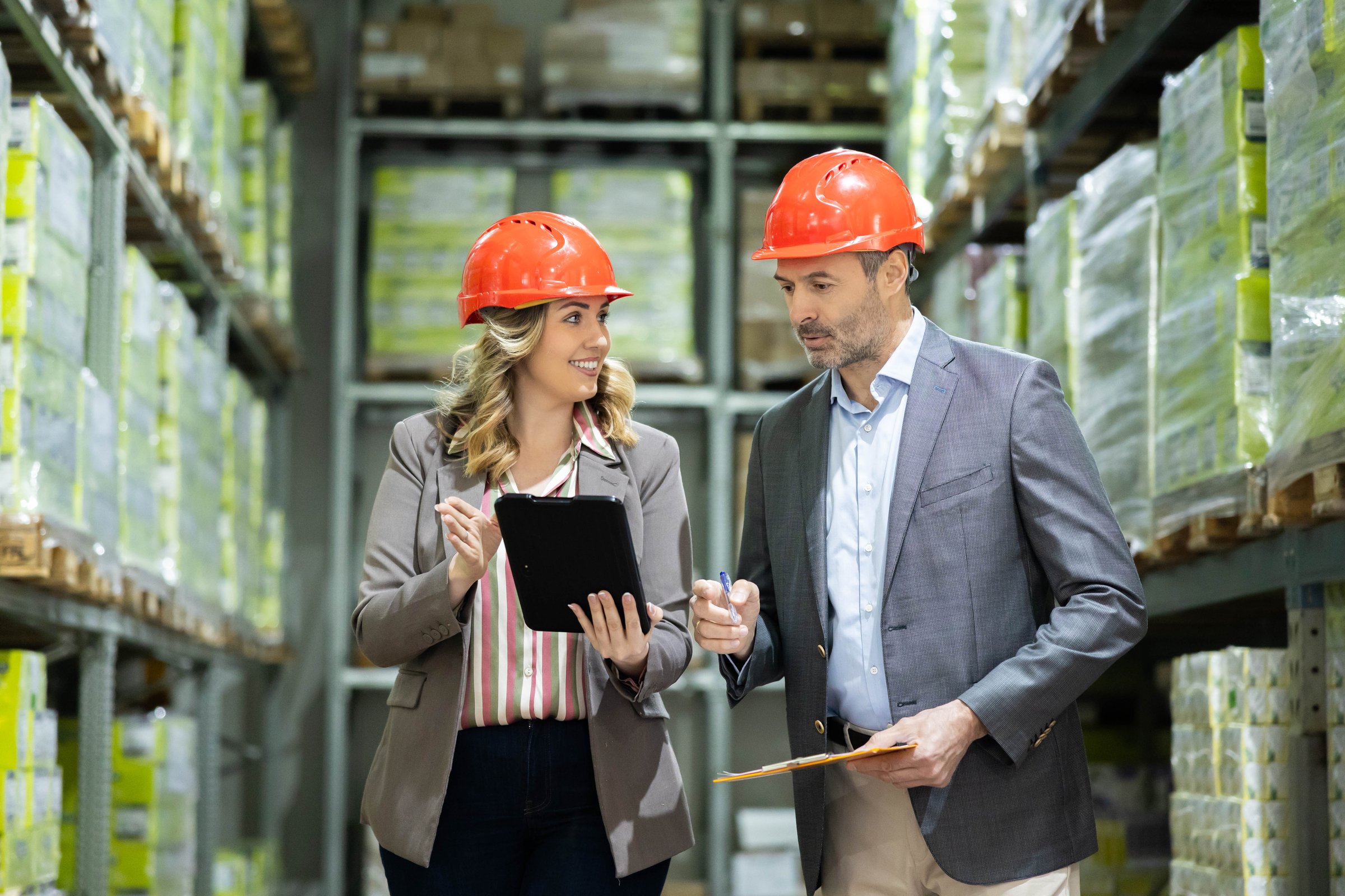 A man and woman strategize and analyze stocks in a warehouse, highlighting teamwork and efficiency in their work environment.