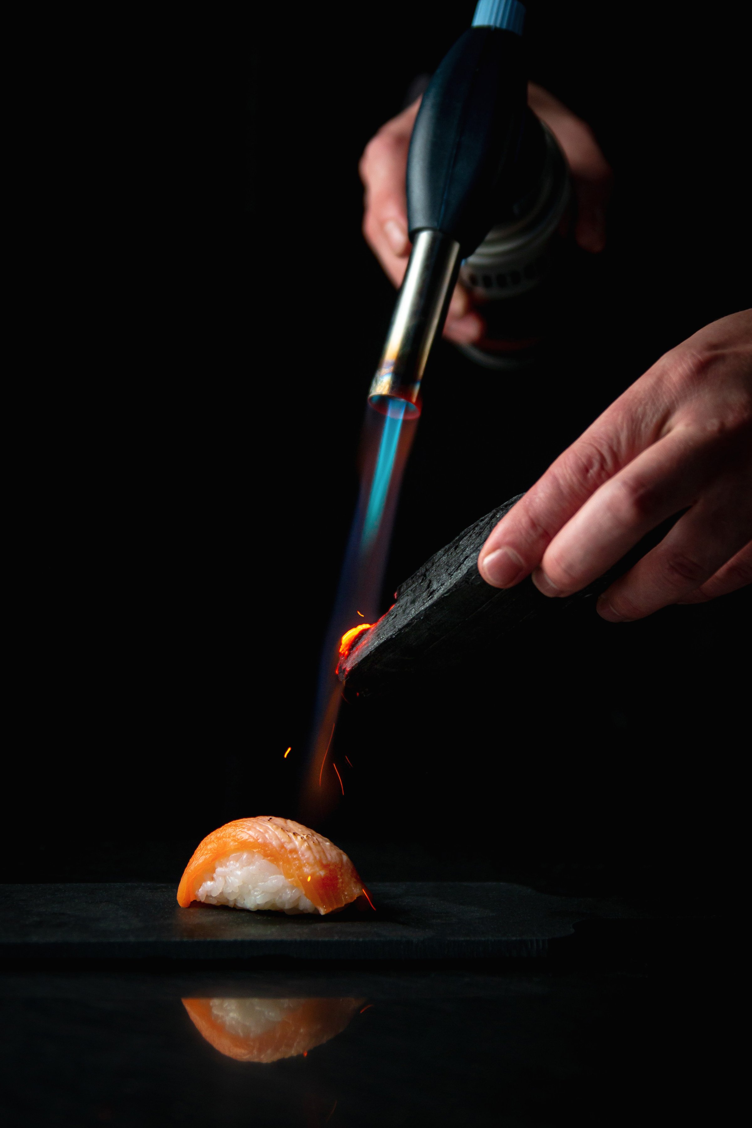 Scorching, Flaming sushi with a torch
Roasting sushi with a burner on a dark background
